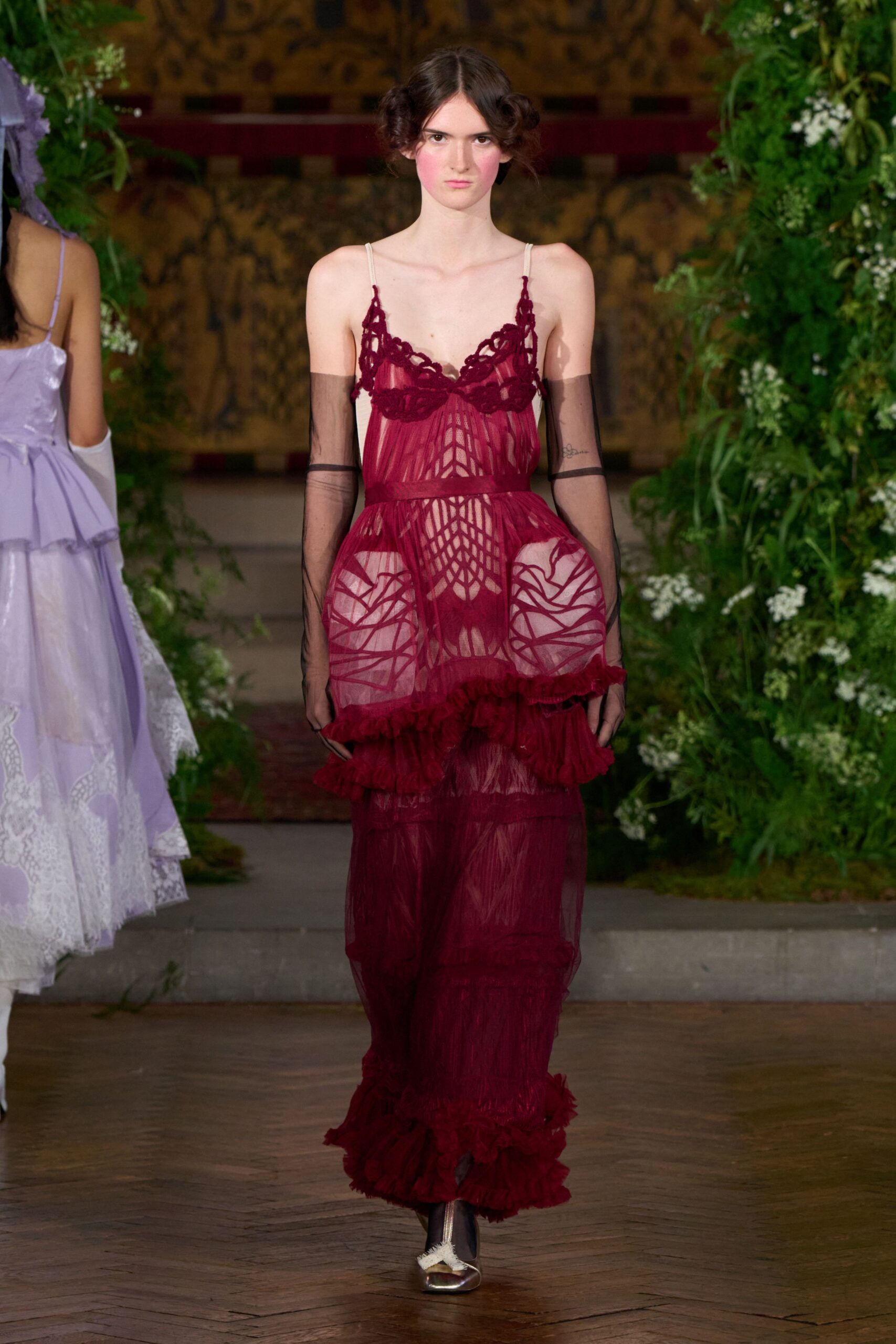 Burgundy sheer mesh slip dress with corded lace cups and ruffled tiers. Smoke tulle opera gloves ending just above the elbow. Black sheer tights. Silver pumps with a little white bow at the vamp. Crossing a winter garden after the wedding, grass damp against the hem.