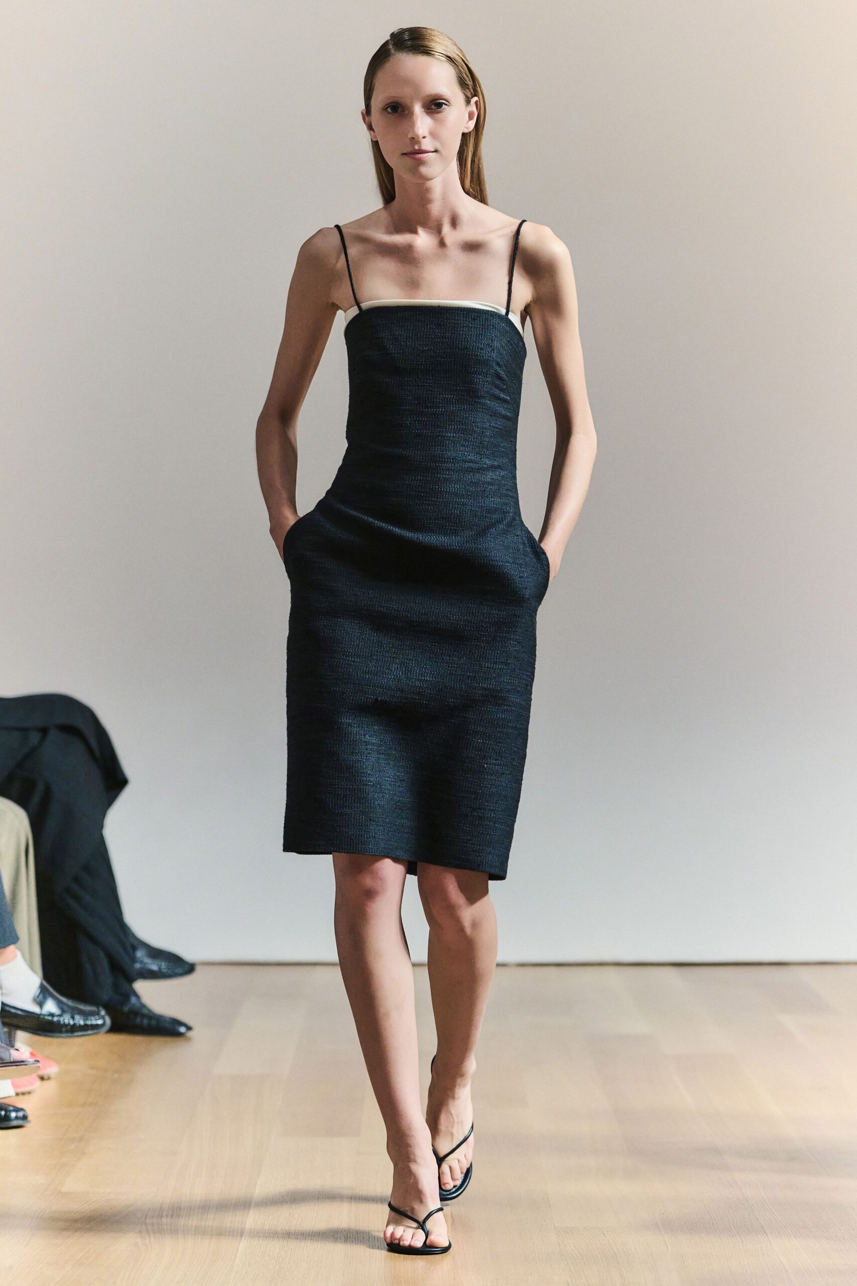 Black sheath dress in nubby weave, white binding tracing the straight neckline. Barely there black thong sandals. For slipping into a courtyard wedding just as the strings begin.