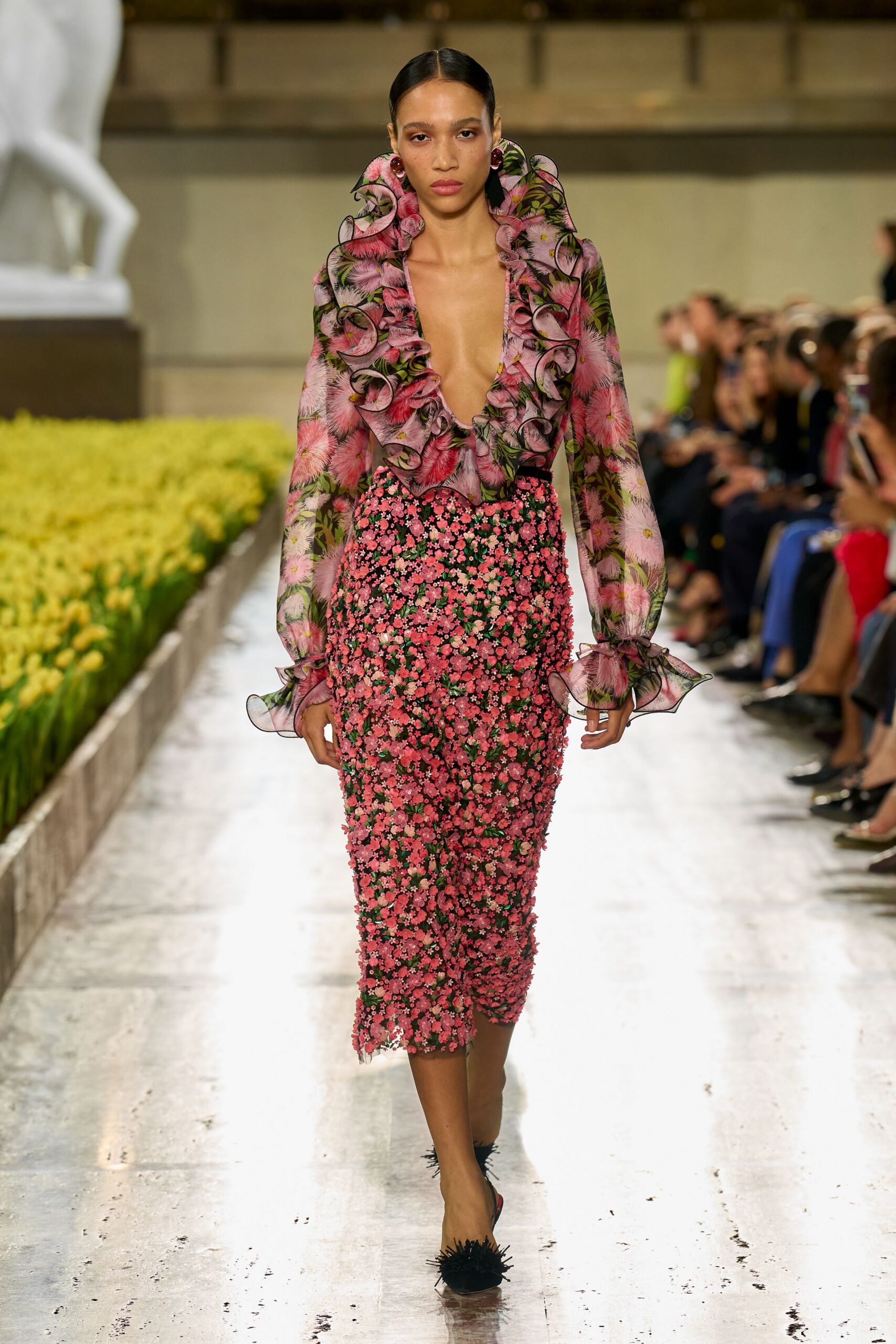 Sheer floral blouse with a plunging V and black-edged organza ruffles. Pencil skirt densely encrusted with tiny pink blossom appliques. Dark cherry cabochon studs. Black mules tipped with wiry fringe. Walking the conservatory path after the camellias have dropped.