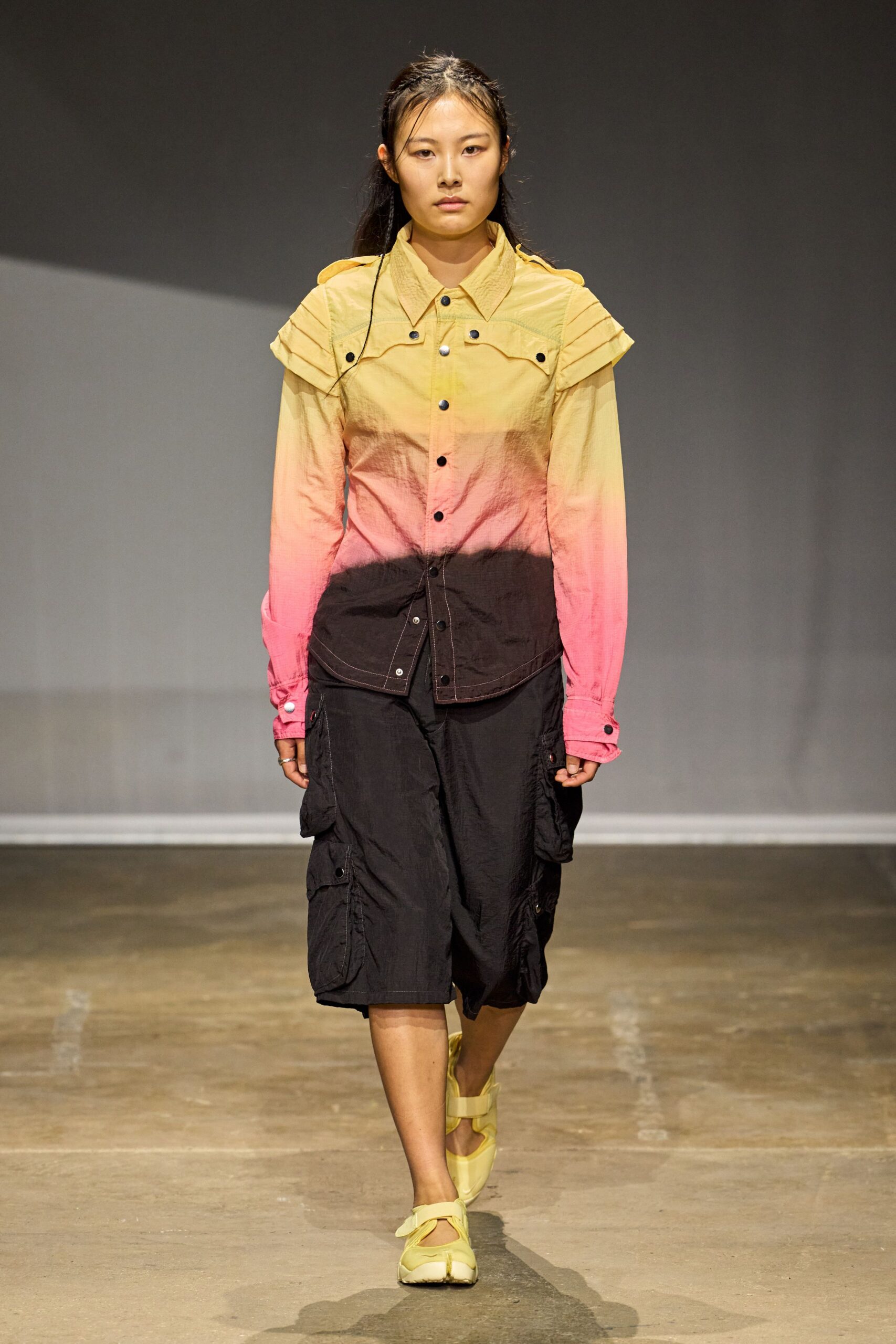 Crisp snap-front shirt fading from butter to pink to soot, pleated cap sleeves. Black crinkled cargo midi, flap pockets bulking out both thighs. Pale yellow Mary Janes with split sneaker soles. Walking the seawall after sunset with salt still drying on your sleeves.