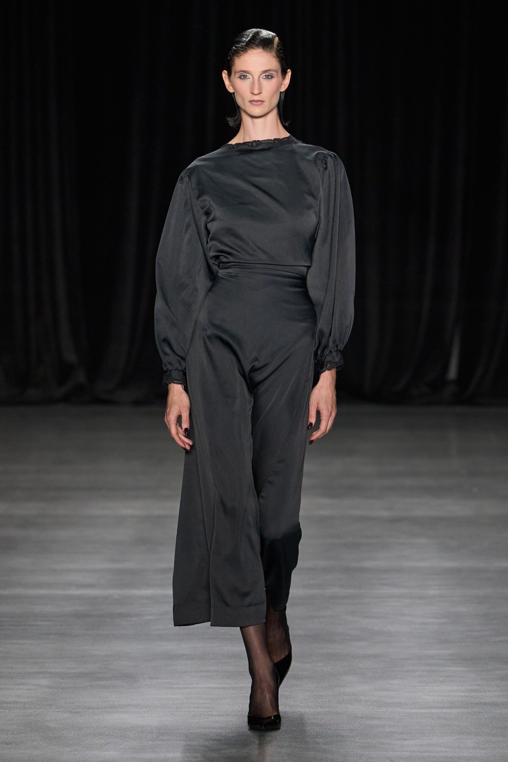 Ink satin jumpsuit with puffed sleeves, lace edging the neck and cuffs. Sheer black stockings. Black patent pumps with a narrow almond toe. Whatever you wear home after the memorial turns into dinner.