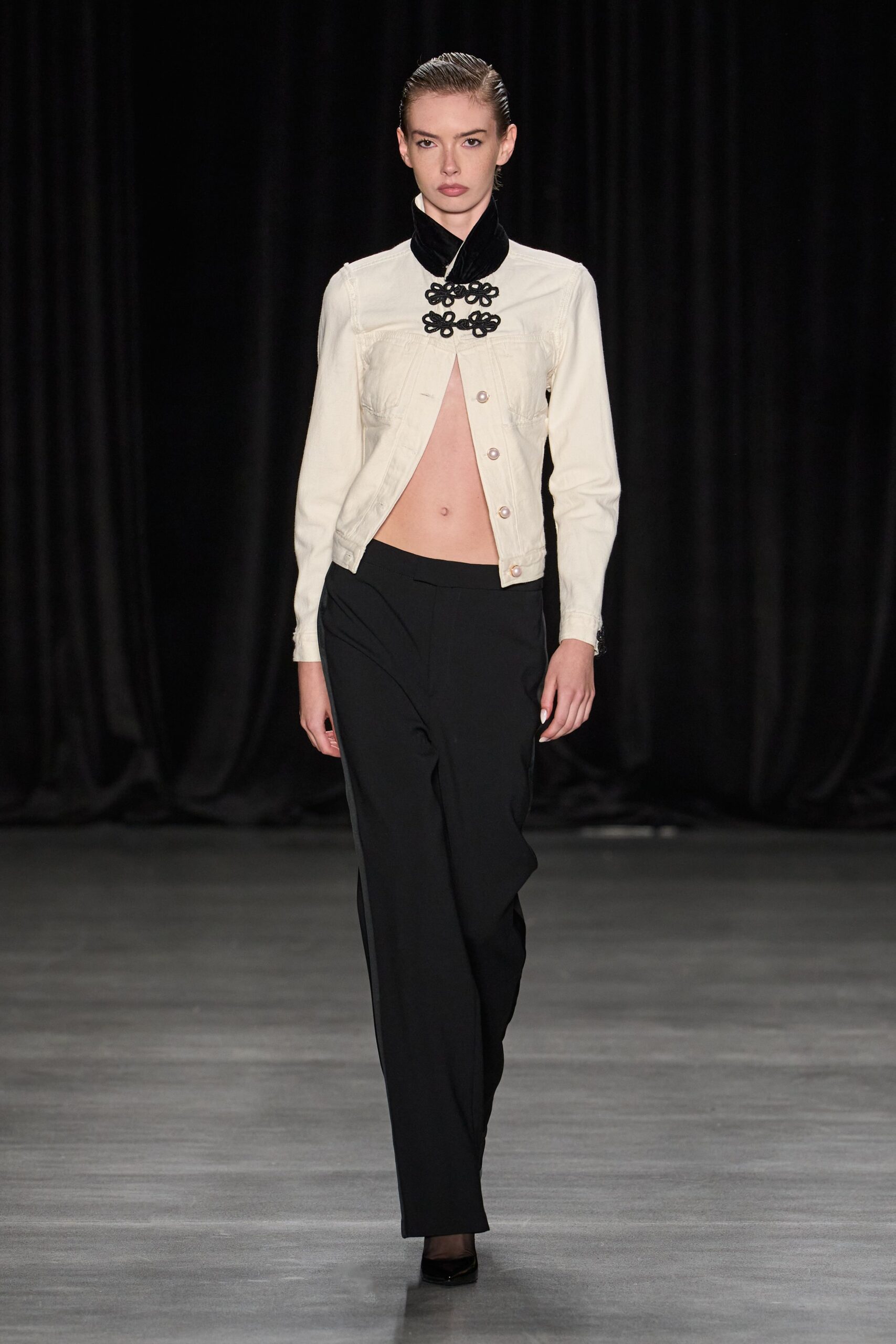 Cream jacket with frog closures, pearl buttons and a sharply split front. Black velvet scarf wrapped high at the throat. Black tailored trousers with a clean flat front. Black pumps under sheer tights. For crossing a hotel lobby after midnight with nowhere to explain yourself.
