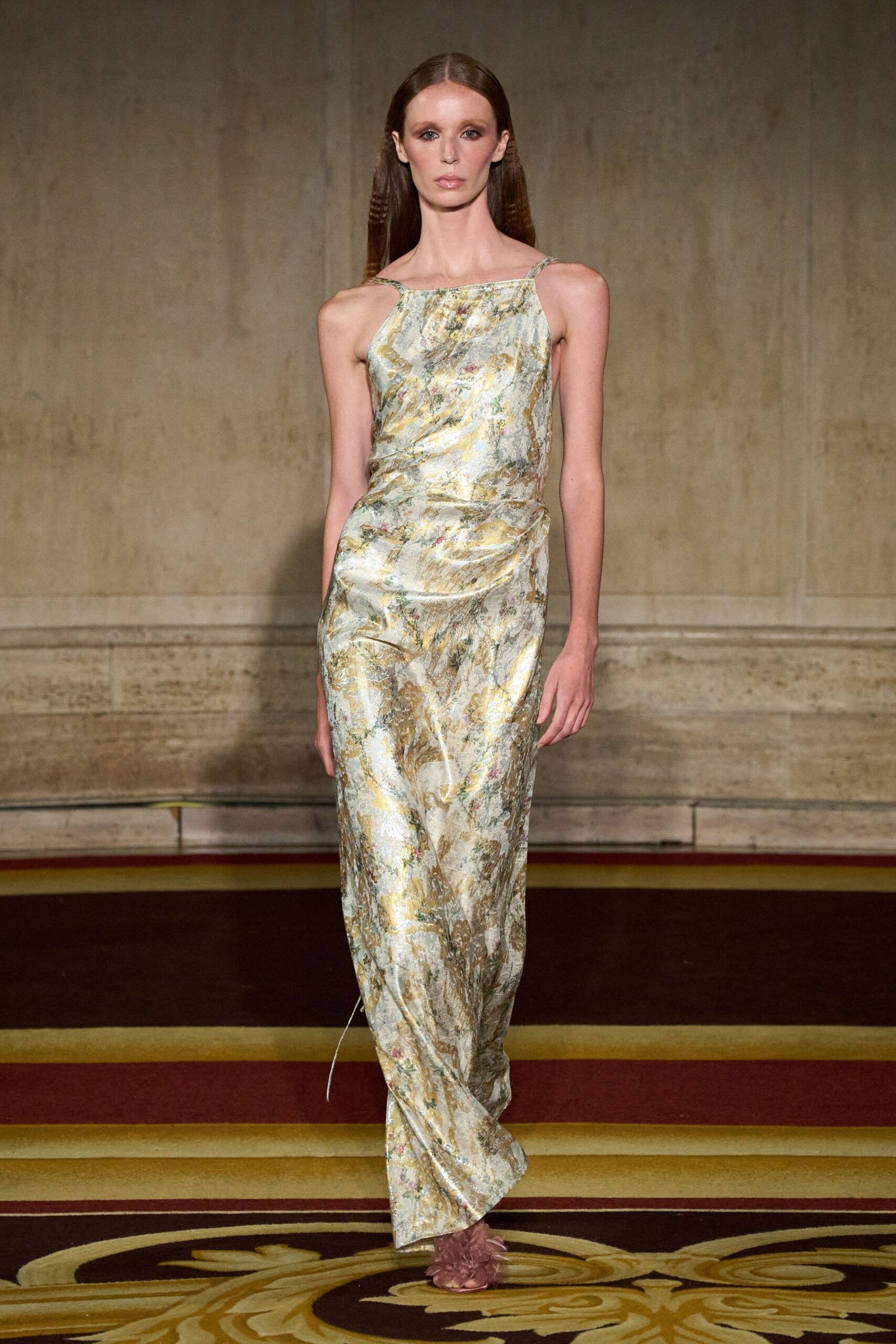 Pale metallic floral brocade slip dress, ruched at one hip with trailing cord. Dusty-rose sandals swallowed by fluffy feather pompons. Crossing a hotel ballroom carpet after the wedding band has packed up.
