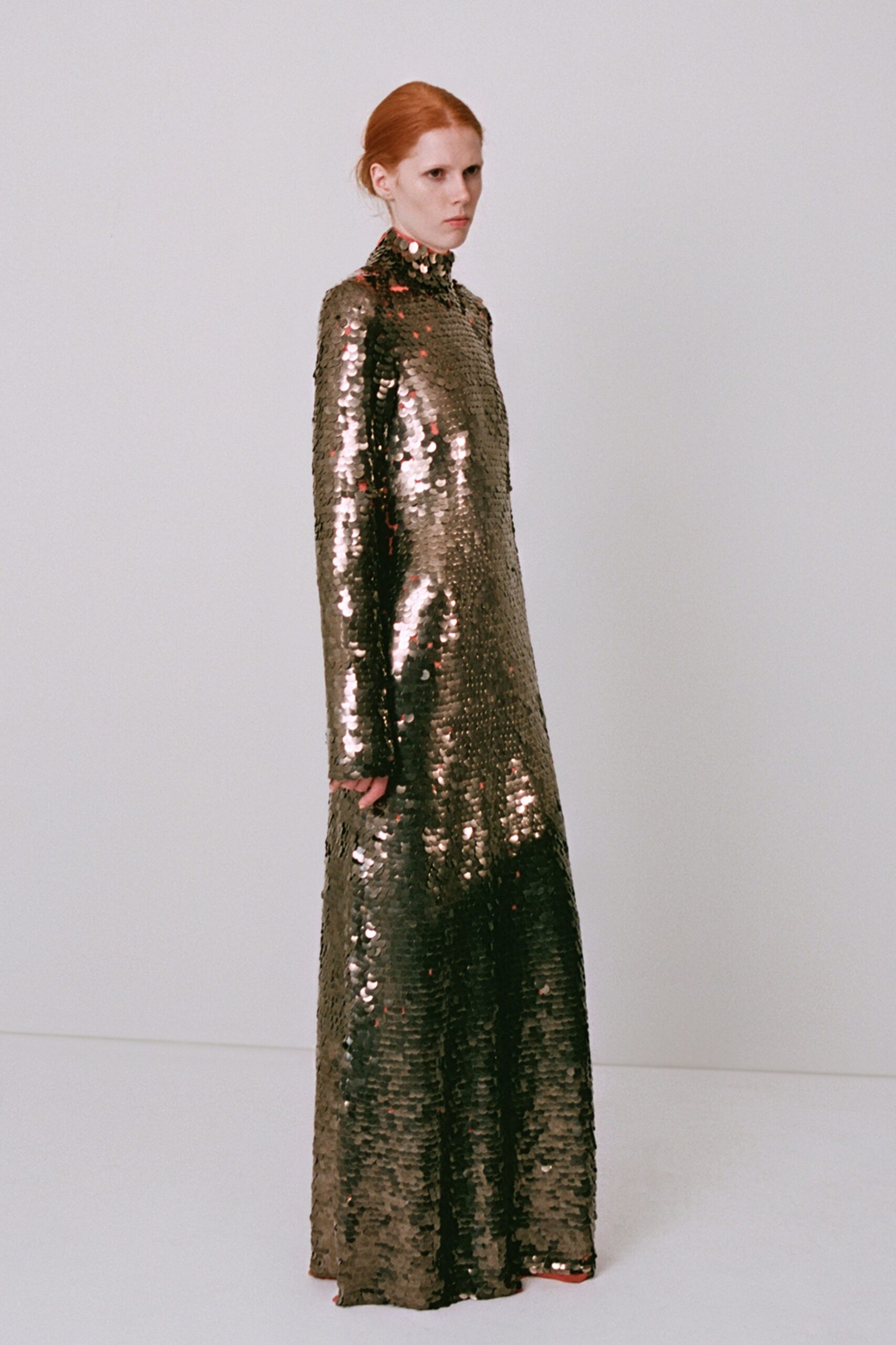 Floor-length column gown in oversized gunmetal paillettes, high neck skimming the jaw. Red pointed toes peeking from the hem. For standing in the museum after hours while the lights hit every wall.