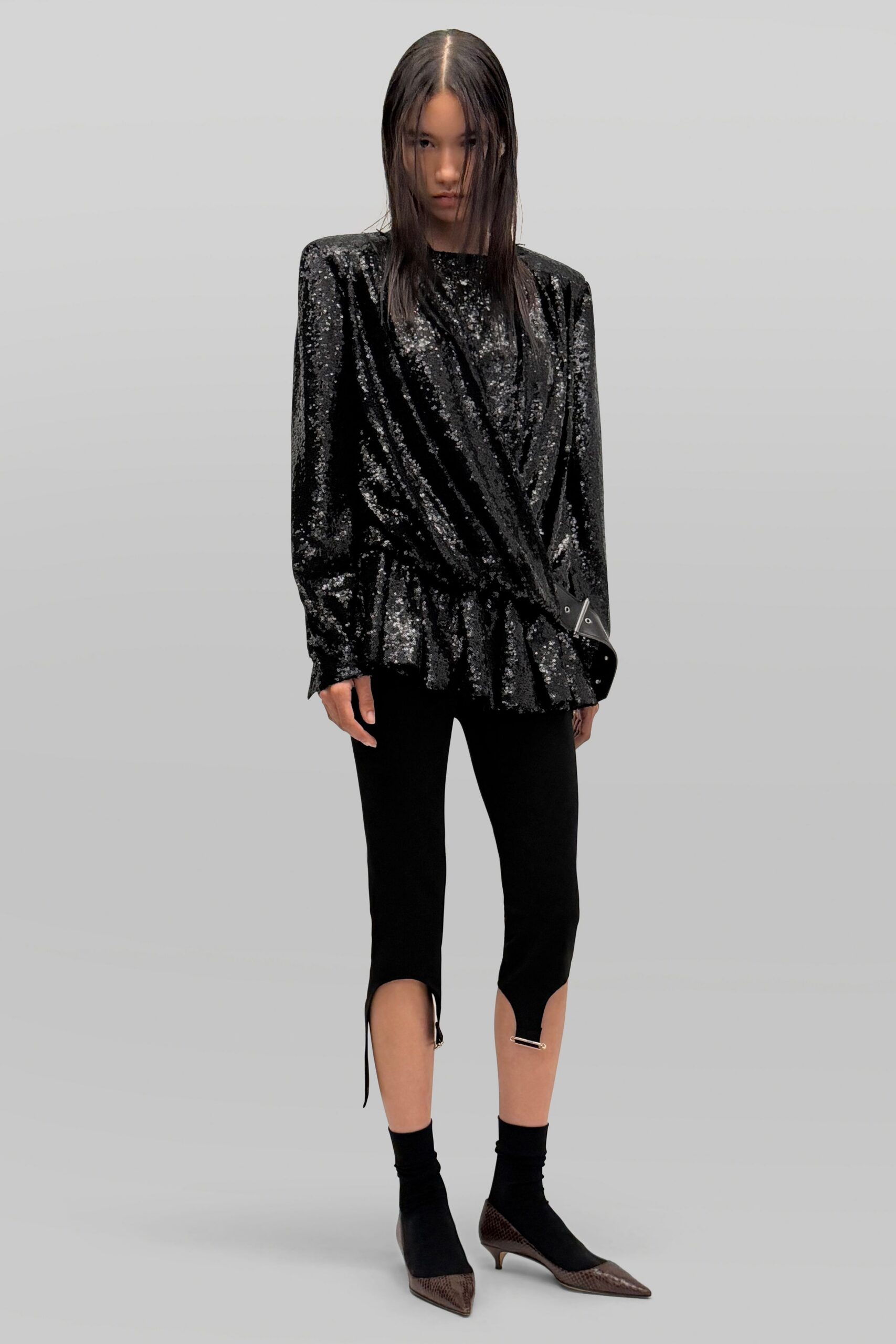 Black sequined wrap top with strong shoulders and a peplum flare. Cropped black leggings slit at the calf, one drawcord hanging loose. Black sock boots with brown python pointed toes and kitten heels. For the hotel bar after midnight, when the lobby flowers are starting to wilt.