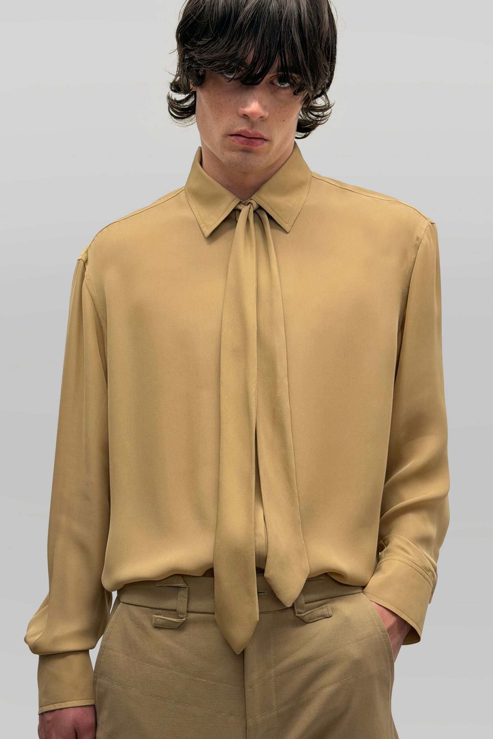 Sandwashed camel blouse with a long scarf tie hanging past the placket. Matching twill trousers with angled belt loops and curved topstitching. For signing the hotel bill after missing the red-eye.