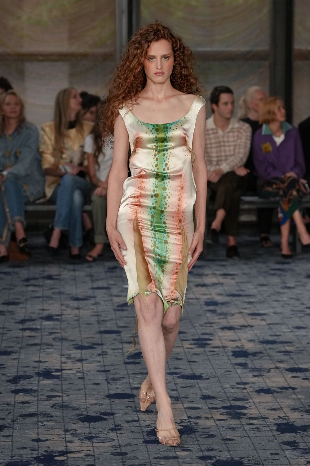 Pearly bias-cut satin slip dress, airbrushed in mint and rust droplets, hem pulled into uneven points. Nude strappy sandals in clear gloss leather. Walking across a hotel courtyard just after the sprinklers shut off.