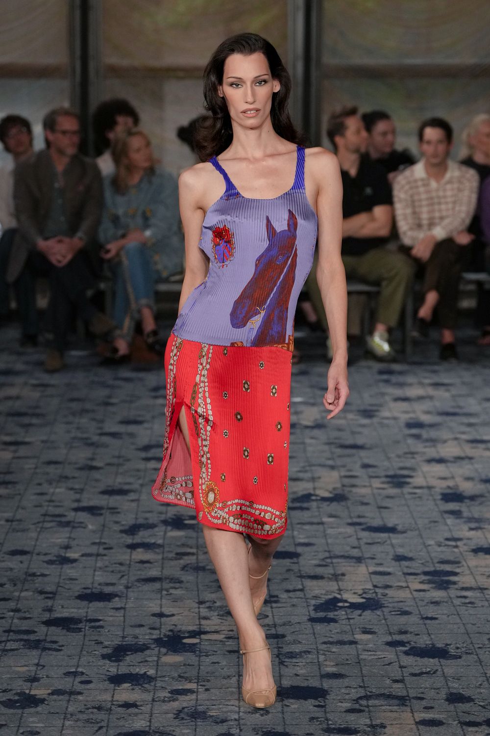 Lilac ribbed tank printed with a chestnut horse and torn rose. Tomato red ribbed midi skirt, scarf-border print curling around the slit. Nude patent Mary Jane heels with a slim instep strap. Walking across a hotel terrace just after the pool towels were cleared.
