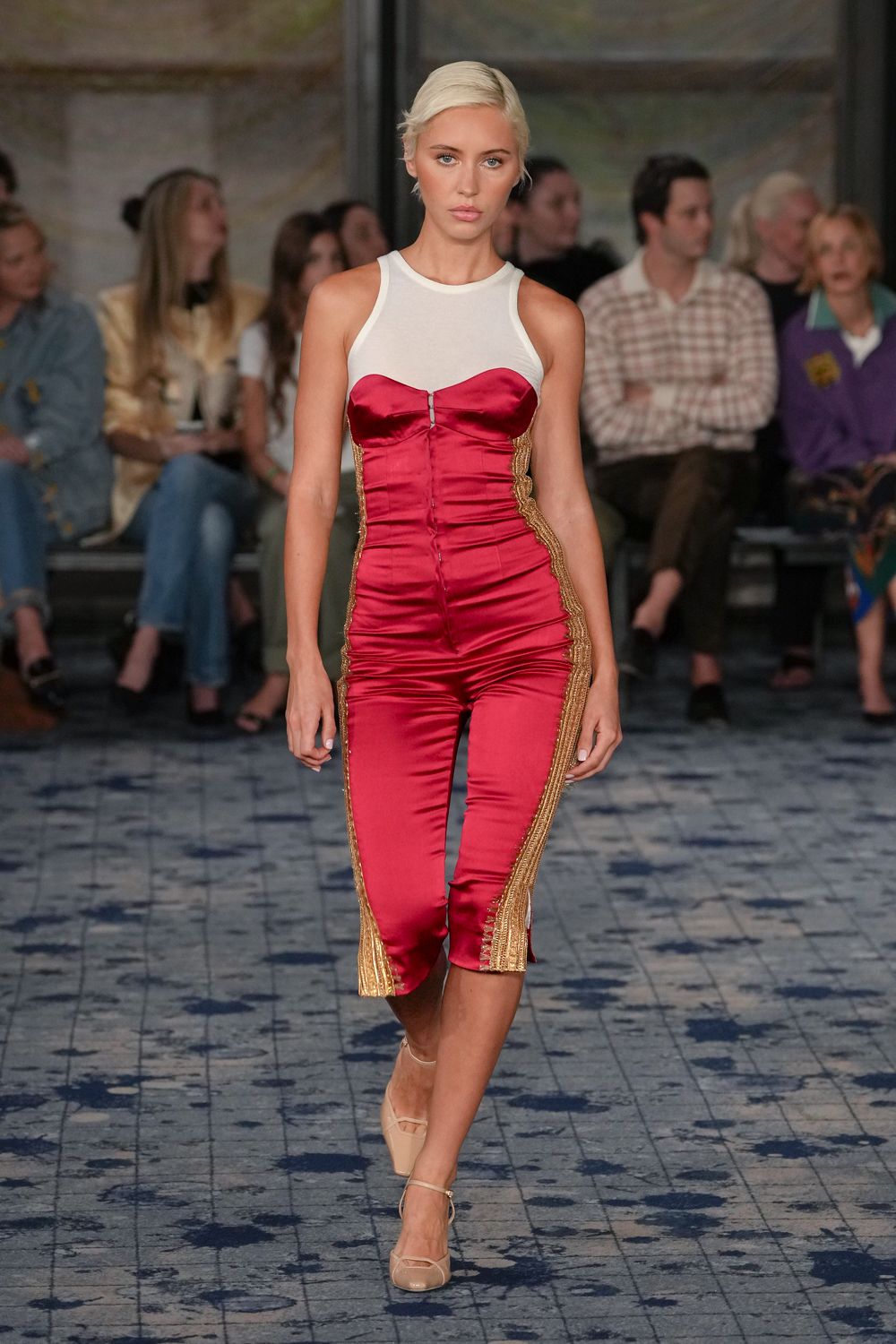 Raspberry satin capri jumpsuit with a white mesh racer bodice. Sweetheart bust edged by a tiny center hook. Gold braided inserts running from underarm to split calf hem. Nude patent Mary Janes with thin ankle straps. Walking into a seaside casino before the carpet dries from mopping.