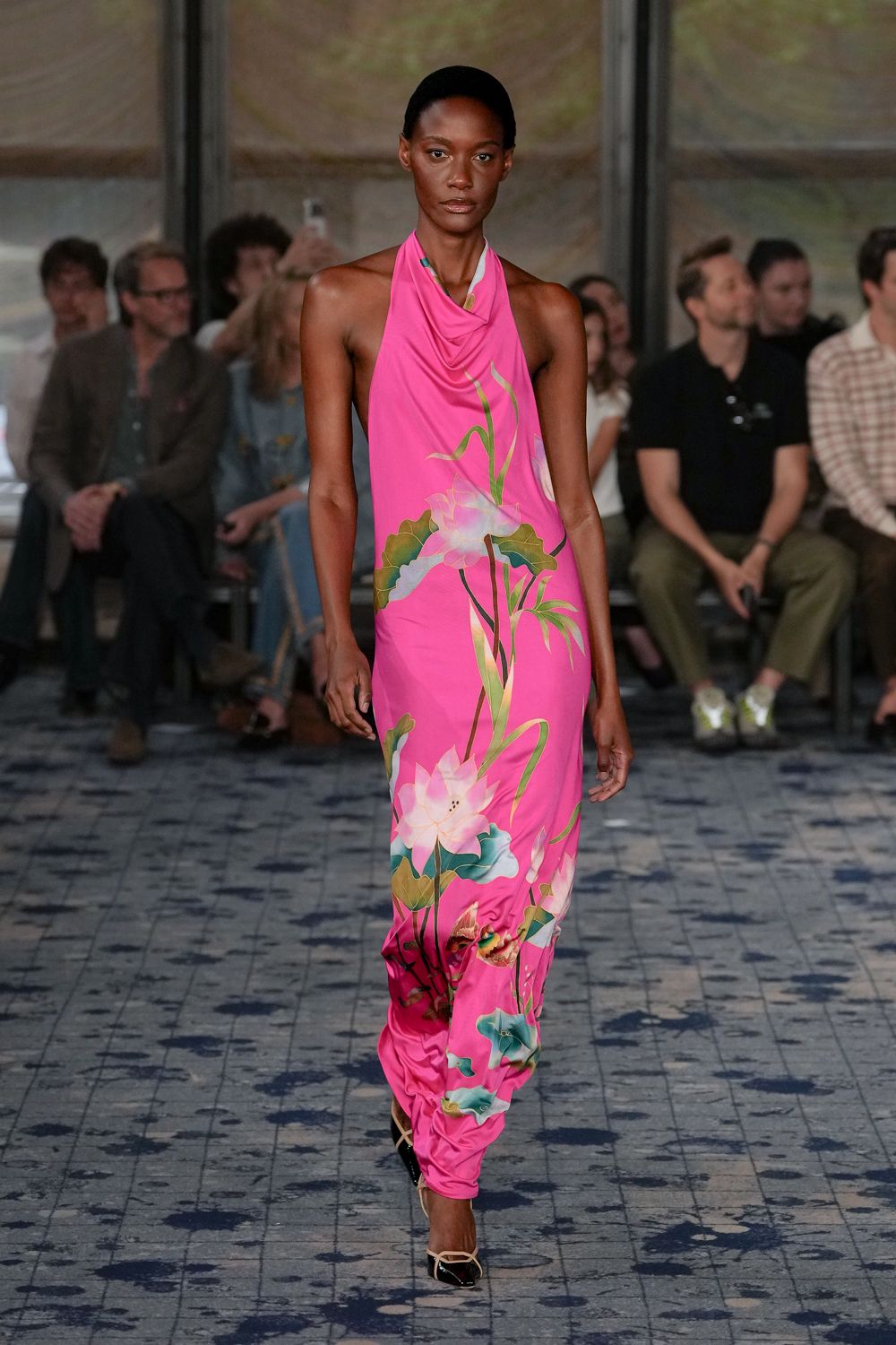 Hot-pink draped halter column, lotus print sliding into a ruched ankle puddle. Black pumps with pale crisscross straps skimming the instep. Hotel courtyard after rain, carrying dessert back before it melts.