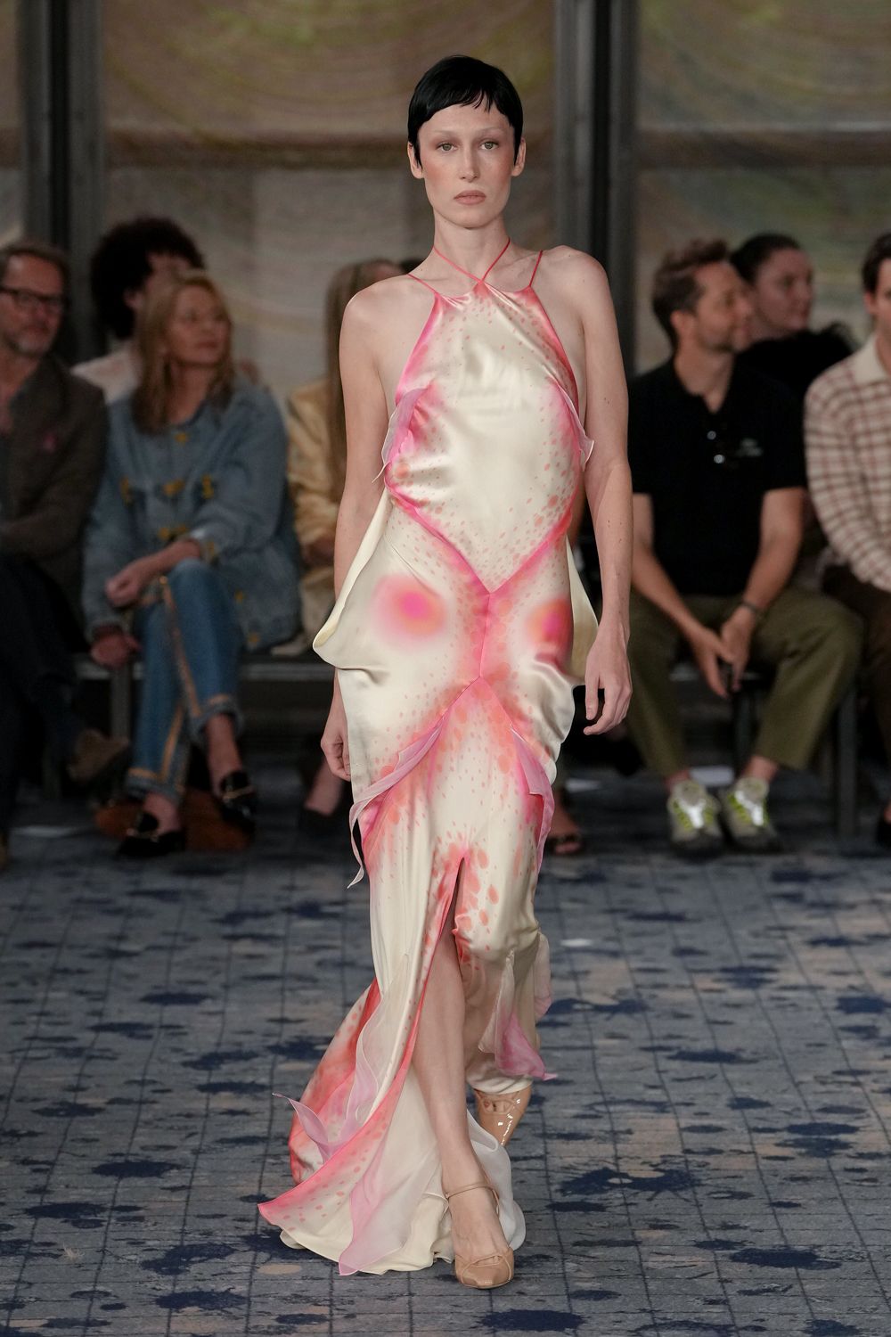 Ivory satin halter gown airbrushed in hot pink, handkerchief panels lifting off the hips. Nude patent pumps with a narrow instep strap. Walking across a hotel terrace just after the sprinklers shut off.