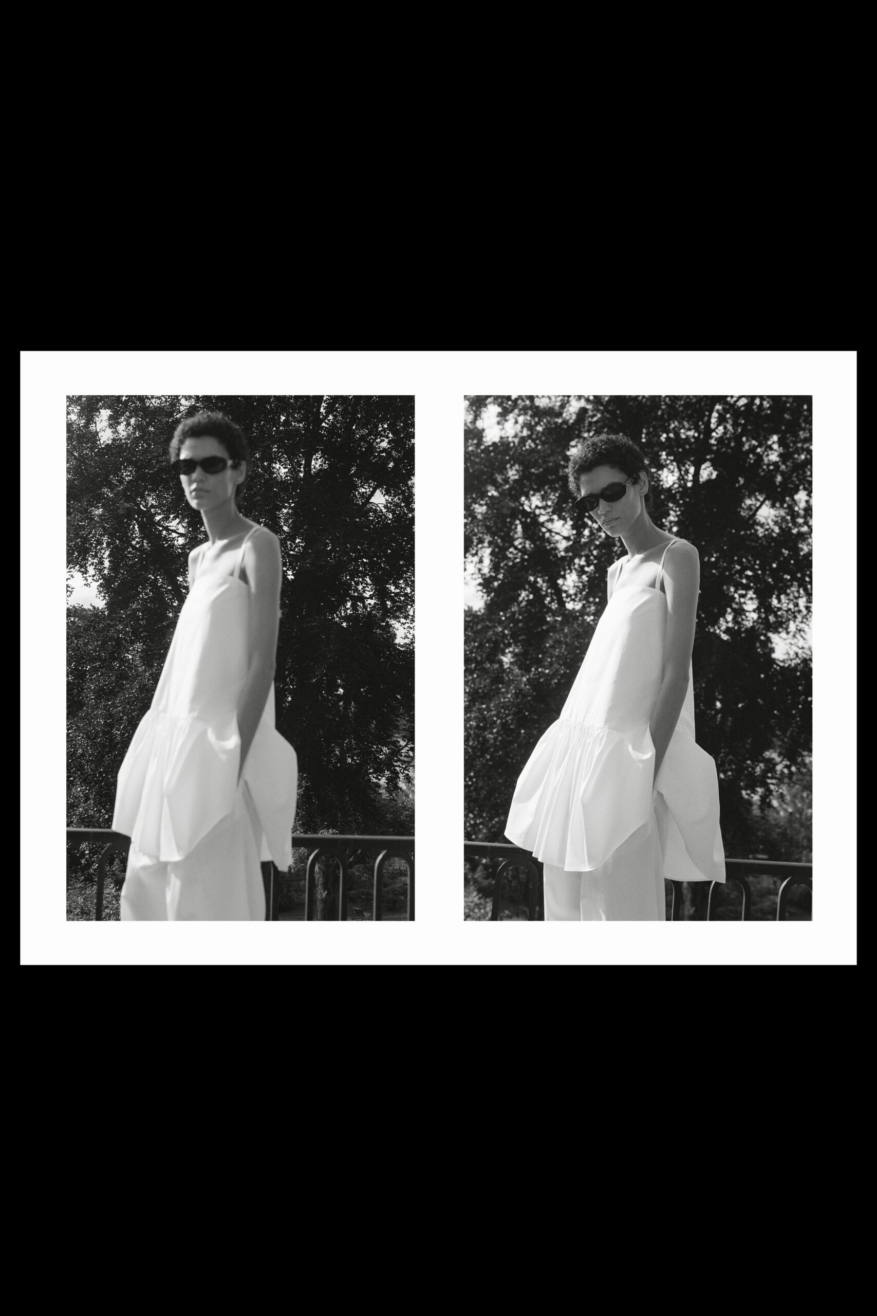 Narrow black wraparound sunglasses. White slip dress with a dropped gathered flounce and hand-deep pockets. Wide white trousers, pooling softly under the dress. Afternoon on a shaded terrace, too hot to sit up straight.