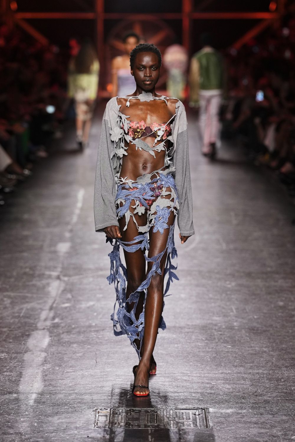 Grey jersey long sleeves spliced to lilac cords and flat floral appliques. Pink embroidered cups peeking through the cutout lattice. Black slip sandals with a sharp red sole edge. Walking home from a beach bonfire with seaweed still stuck to your ankle.
