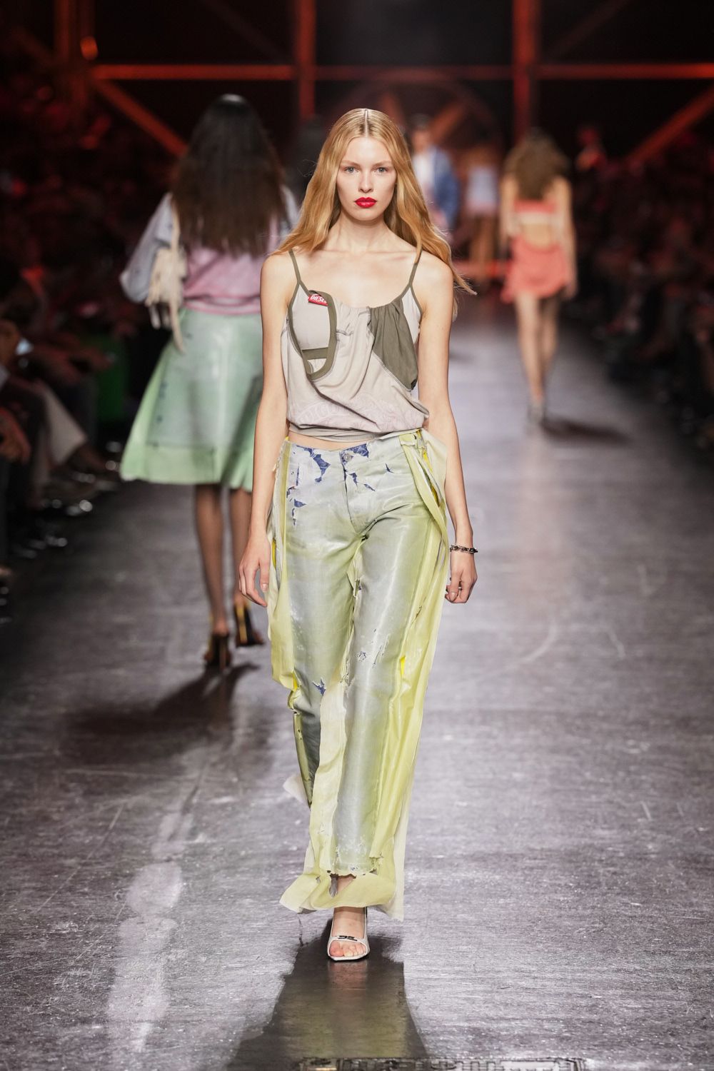 Draped dove camisole with olive bra cups left hanging outside. Pale printed trousers veiled in citron chiffon panels, hems chewed away. White slide sandals with a tiny black flourish across the toe. Narrow silver chain bracelet. For crossing a ferry deck after rain, hair still salted stiff.