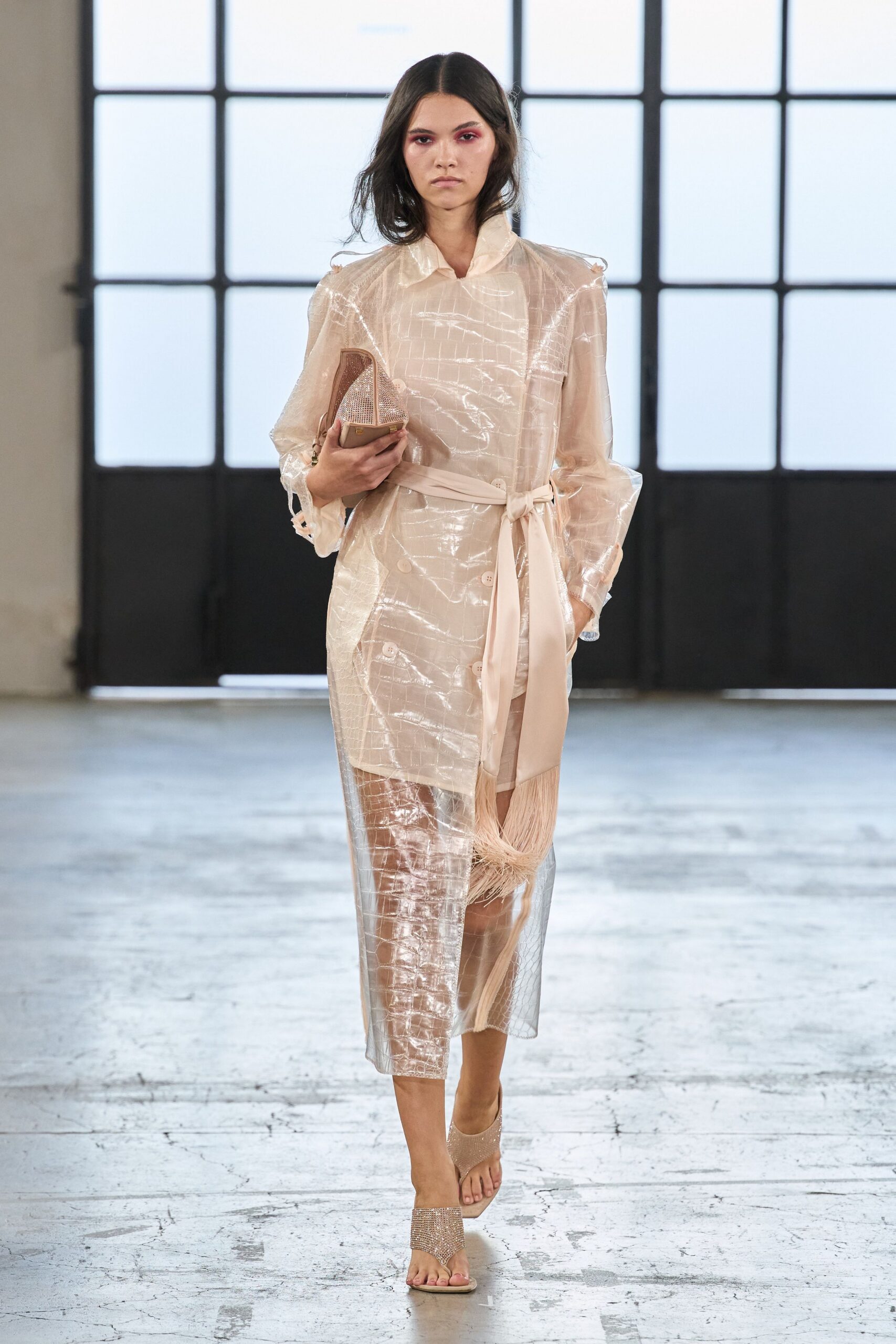 Transparent blush crocodile-embossed coatdress, double-breasted under a long sheer panel. Self-tie sash with fringe swinging from one end. Nude minaudiere crusted with tight rhinestone mesh. Barely there thong sandals with glittering vamp bands. For crossing a hotel lobby still damp from the pool.