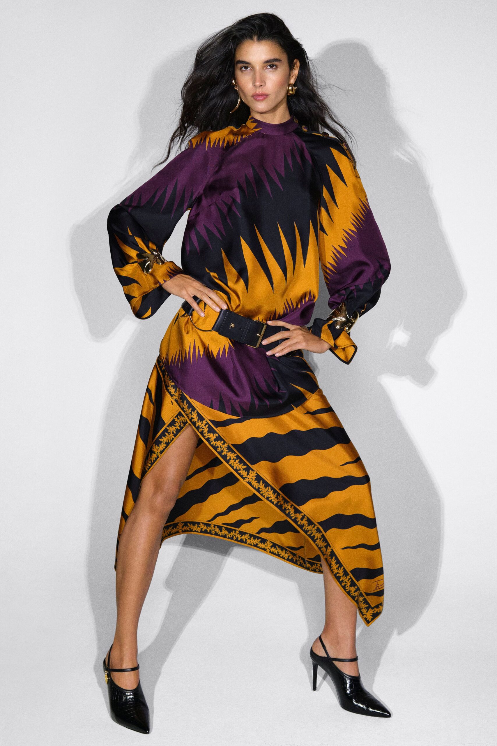 Printed satin dress in aubergine, black and marigold, with a mock neck, blouson sleeves and an asymmetric scarf hem edged in a tiny vine border. Wide black belt, croc-embossed slingback pumps. Hotel corridor, midnight, looking for ice.