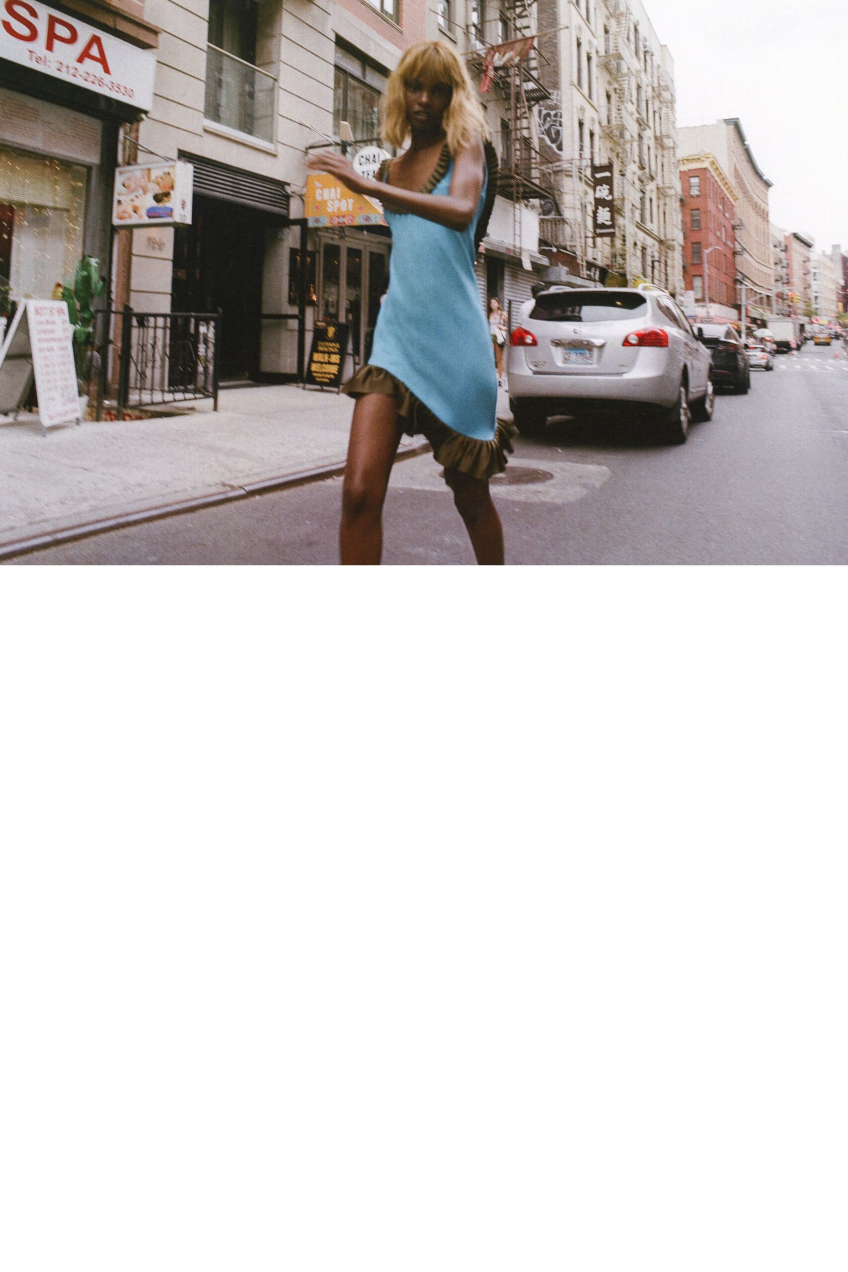Sky-blue slip dress cut on the bias, olive ruffle kicking past one thigh. Olive ruched straps edging the low neckline. Crossing Chinatown traffic with a cold drink sweating in your hand.