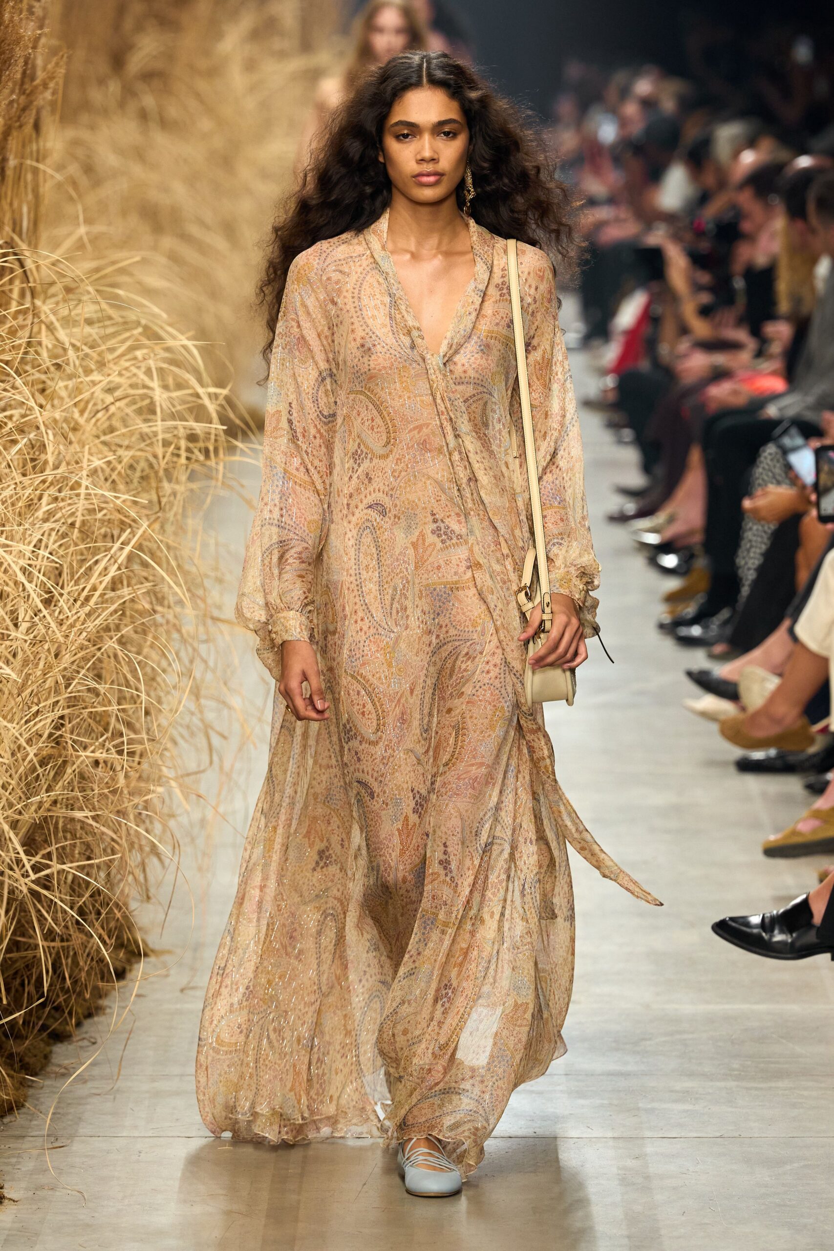 Sheer sand chiffon maxi dress, washed paisley and a loose scarf tie. Cream leather box bag on a narrow strap. Pale lace-up flats with crisscross ties over the instep. Single dangling earring. Walking back from a beach wedding with grass seeds on the hem.