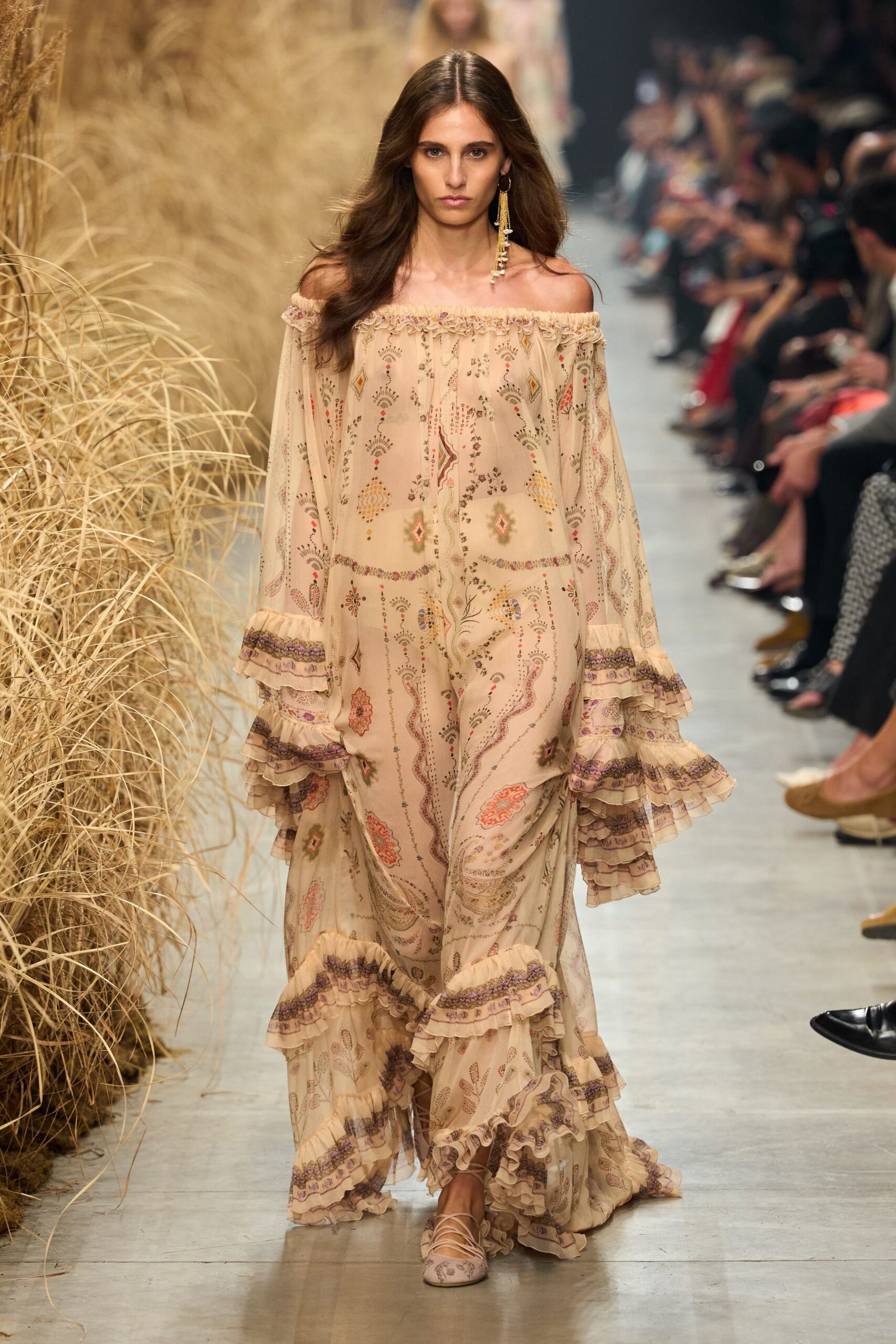 Blush printed chiffon dress worn off the shoulder, sleeves ending in tiered ruffles. Single tassel earring with dangling pearl strands. Printed ballet flats crisscrossed with pale ankle ties. Walking through dry meadow grass after a wedding that ran past sunset.