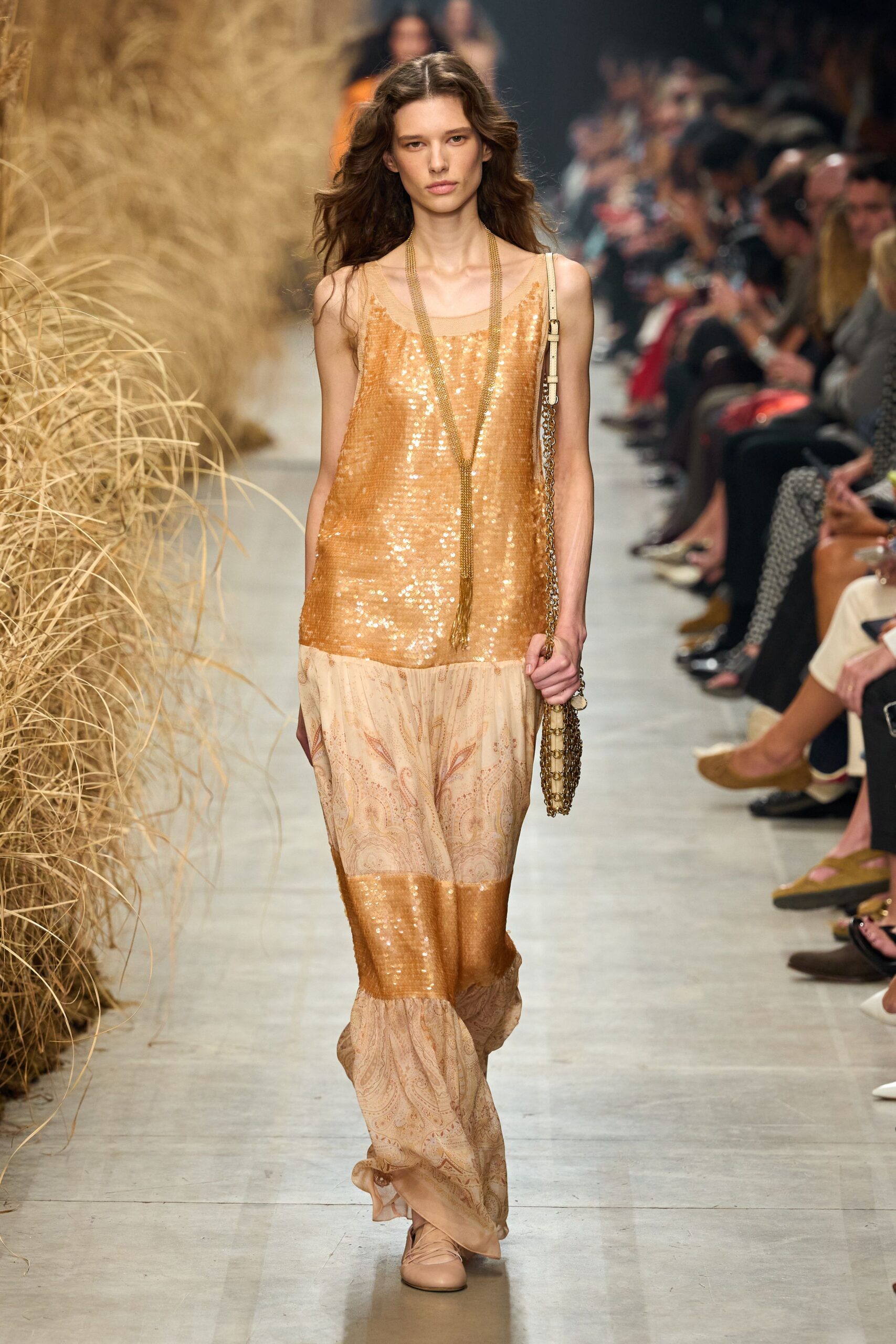 Apricot sequined slip dress spliced with blush paisley chiffon panels. Long gold chain fringe dropping nearly to the waist. Cream shoulder bag with a heavy brassy chain strap. Nude ballet flats with crossed ribbons over the instep. Walking out of a beach hotel ballroom after the wedding band stopped.