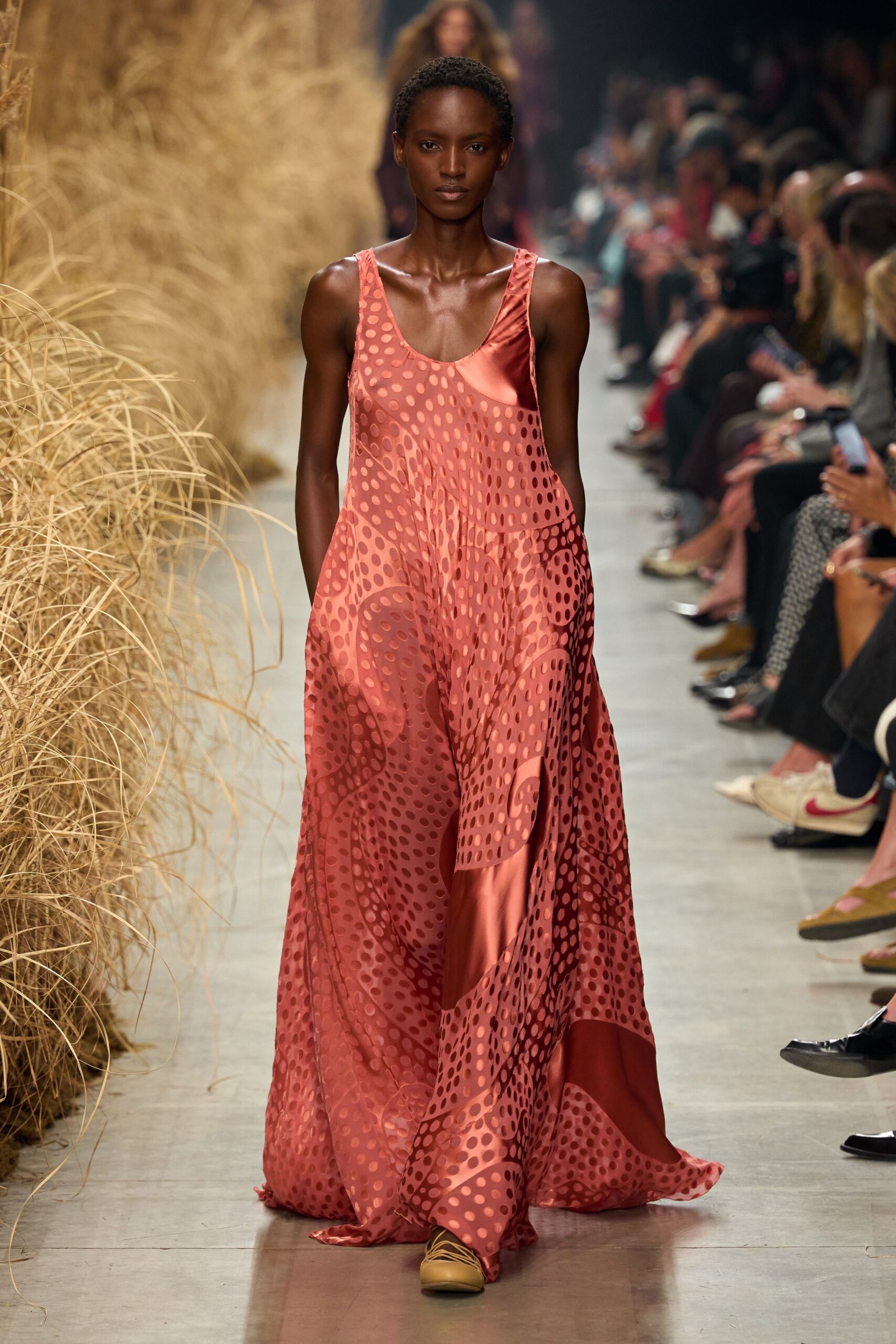 Coral satin tank dress cut loose, overlaid with flocked polka-dot swirls. Mustard lace-up flats peeking from the pooling hem. Walking the dune path after sunset, dress catching burrs and dry grass.