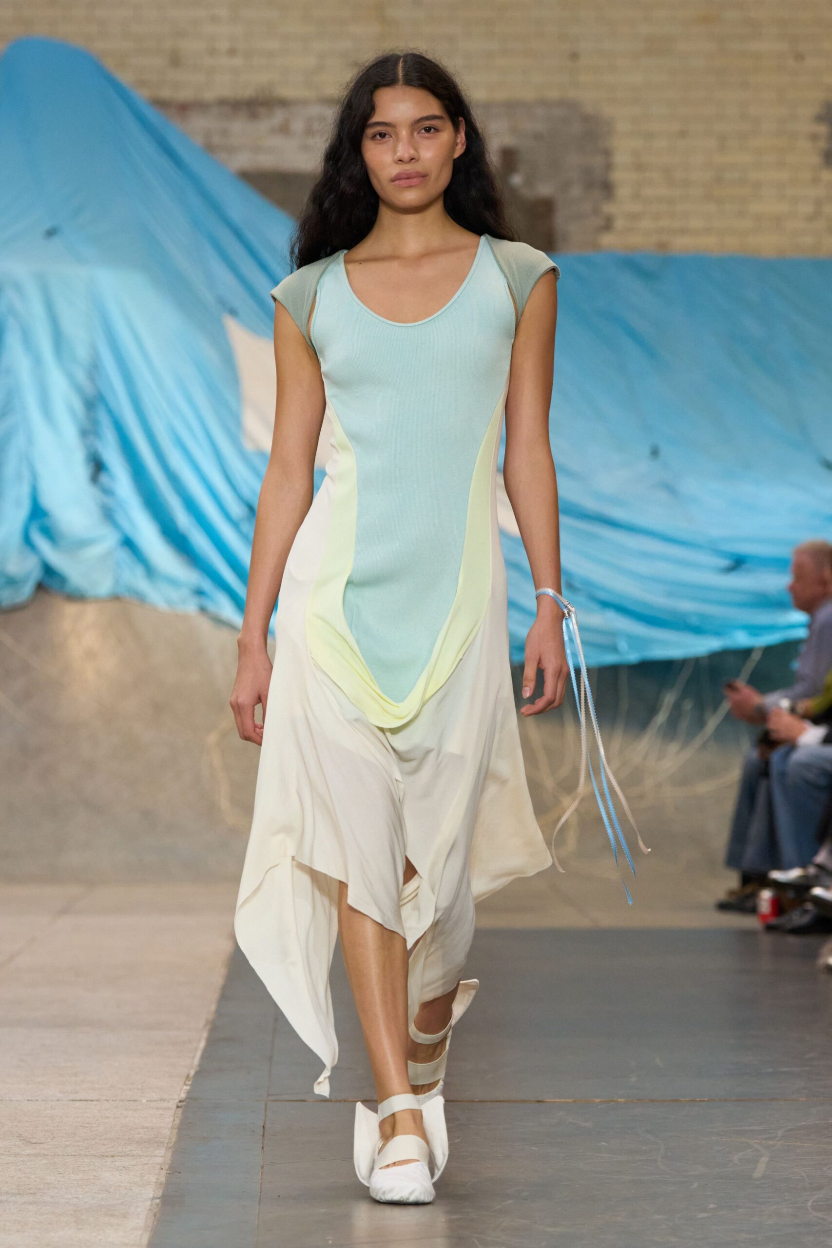 Powder-blue ribbed bodice melting into cream drape, chartreuse panels pooling low. Pale cords trailing from a slim silver cuff. White gathered flats with broad elastic instep straps. Walking past tarped boats before the marina opens for summer.