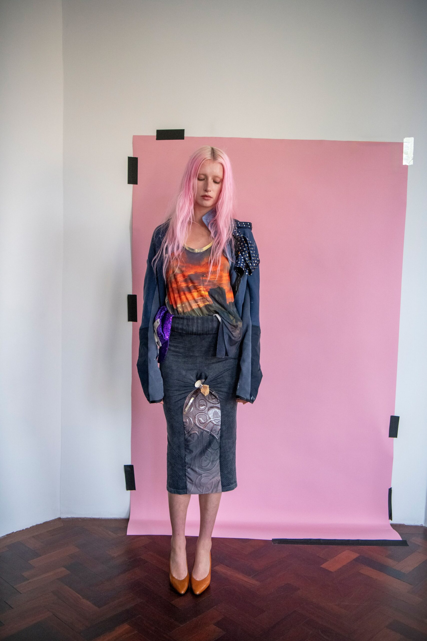 Slouchy slate jacket with a studded scarf panel drooping off one shoulder. Sunset-print tank, one side knotted and dragging below the waist. Charcoal pencil skirt with a ruched brocade panel pinned by shells. Cognac leather pumps. What you wear to water the plants in an apartment borrowed for August.