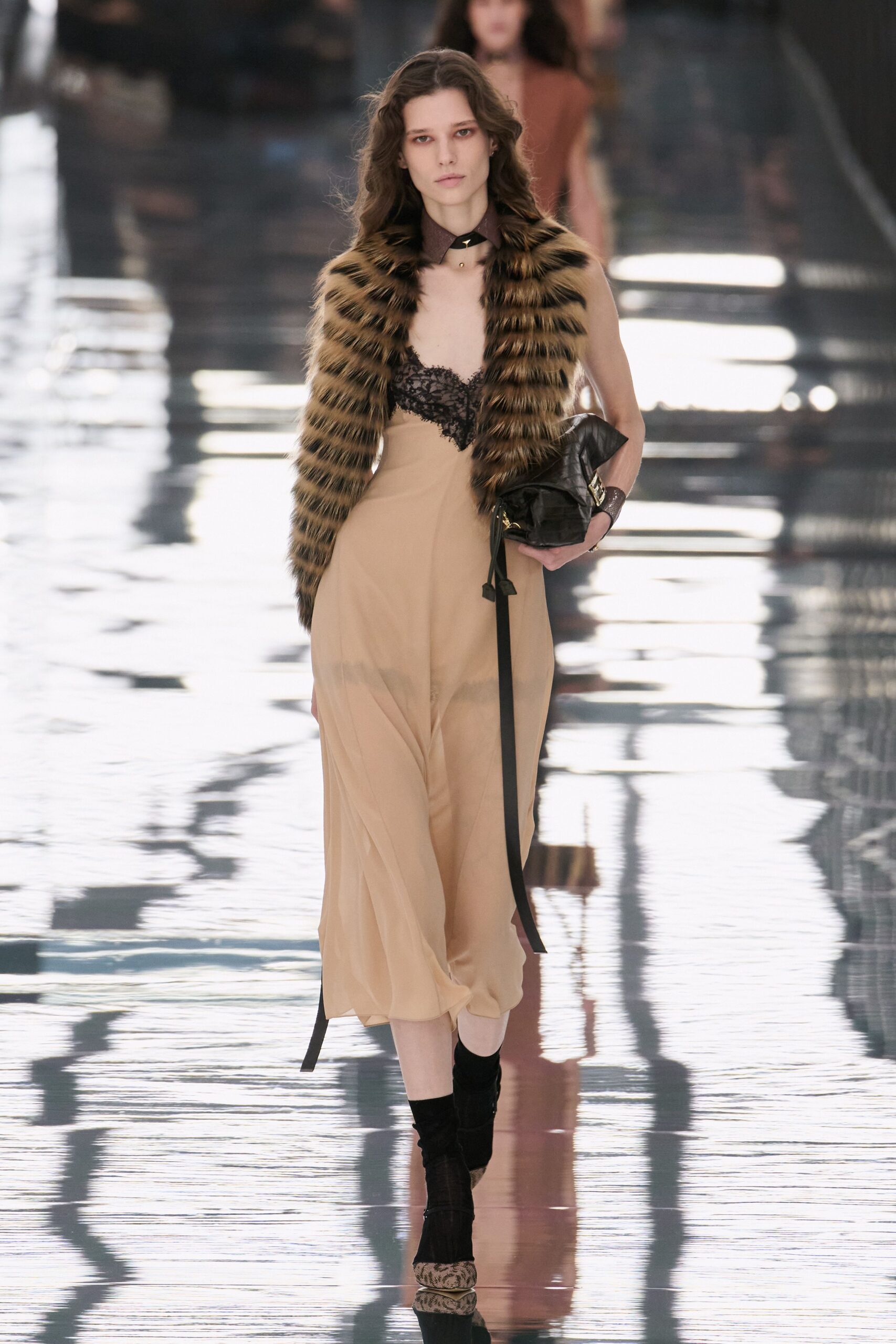 Bandit-striped fur stole hugging the shoulders. Nude chiffon slip dress with black lace cups. Black leather choker with a small gold drop. Crushed black leather clutch, long strap hanging loose. Black ankle boots with pale python toes. Walking the hotel corridor after midnight, still carrying your shoes in your hand.