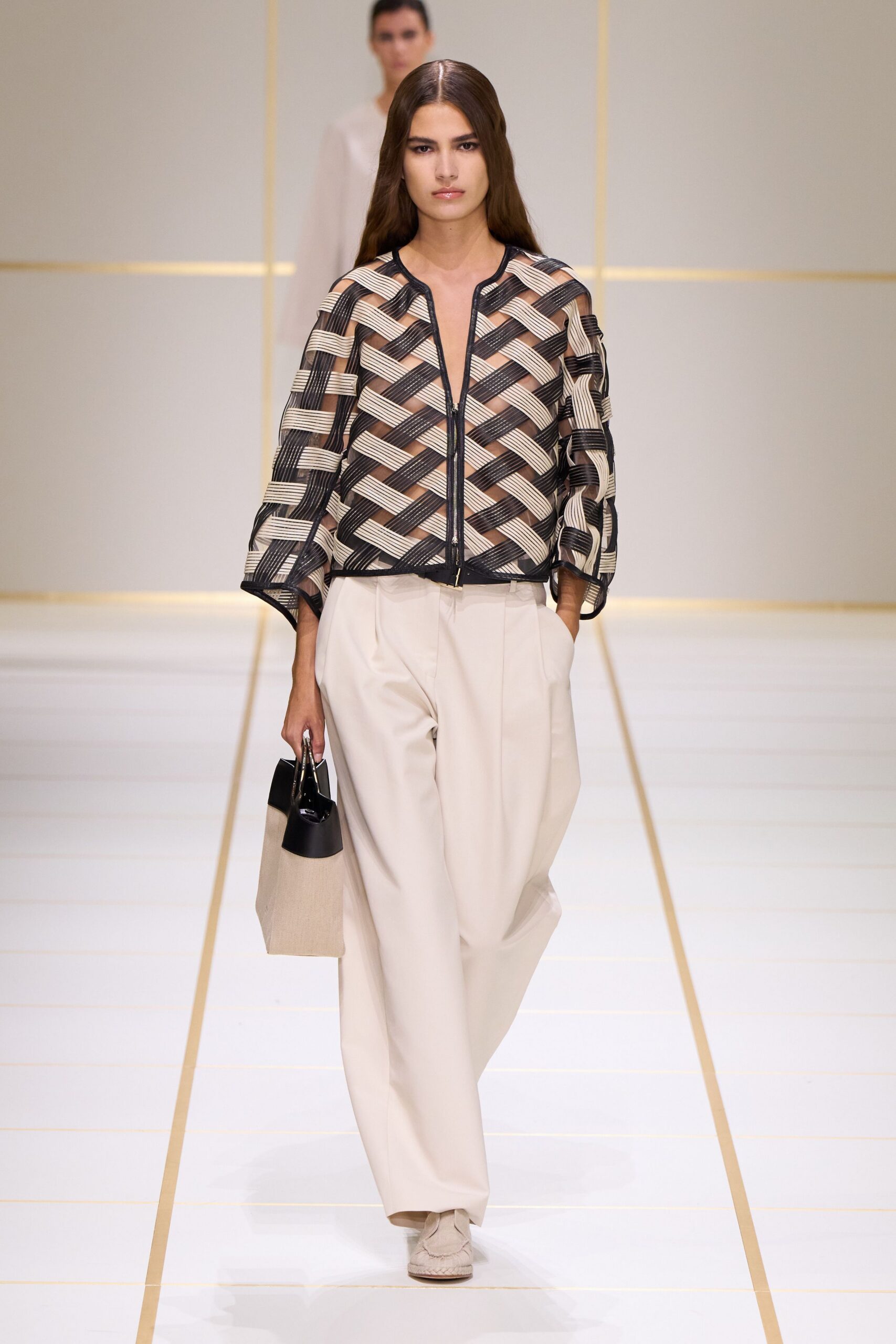 Sheer black organza jacket banded with basket-woven cream grosgrain, zip centered. Cream wide-leg trousers with deep front pleats and a loose break. Structured tote in black leather and coarse oat canvas. Cream moccasin flats with raised whipstitch around the toe. Walking through a hushed museum atrium before the cafe opens.