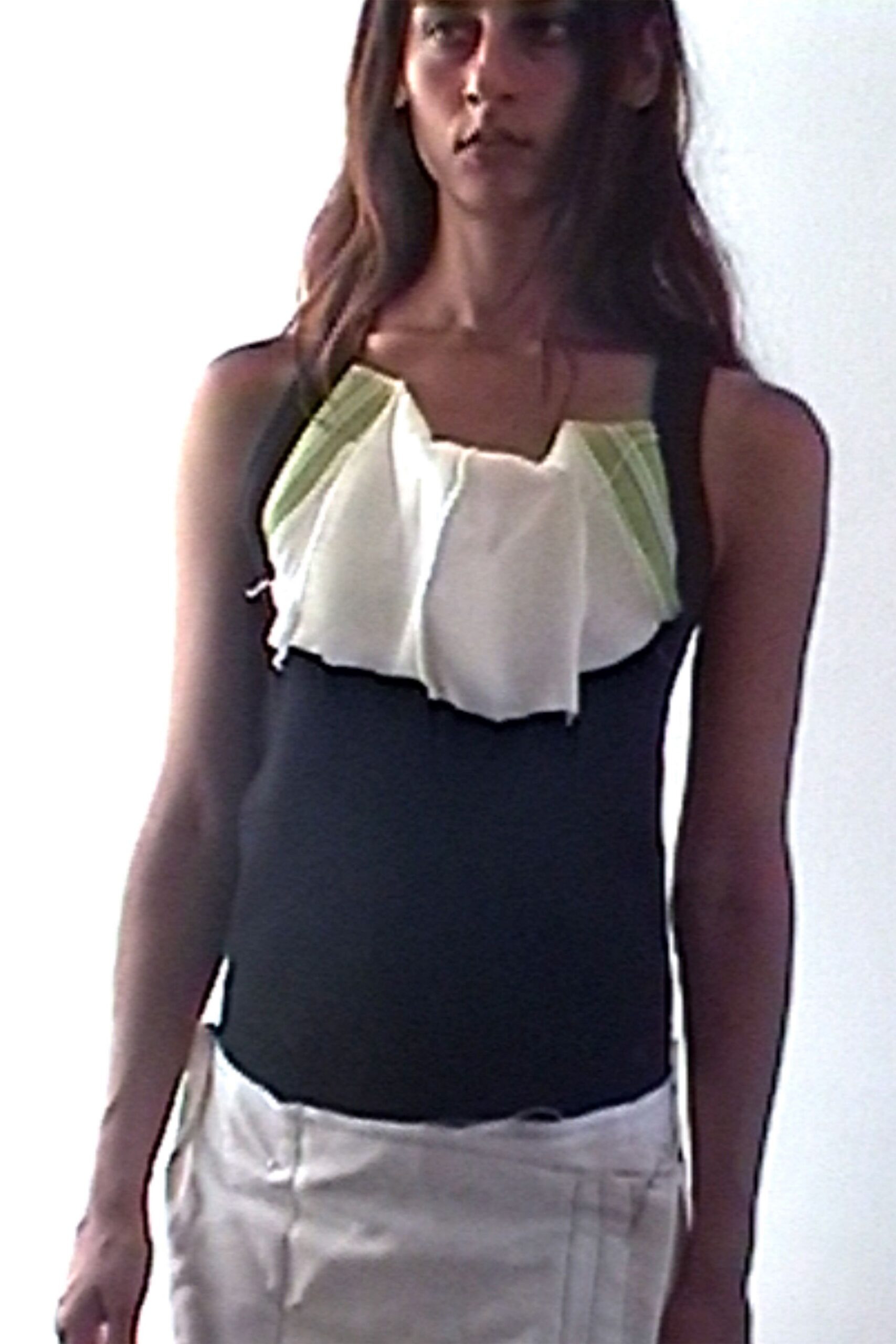 Black camisole top with a chalk ruffle bib edged in pale celery pleats. White low-rise trousers with pressed front seams and a tiny dark tab at the waist. For crossing a ferry deck before the sun burns off the haze.
