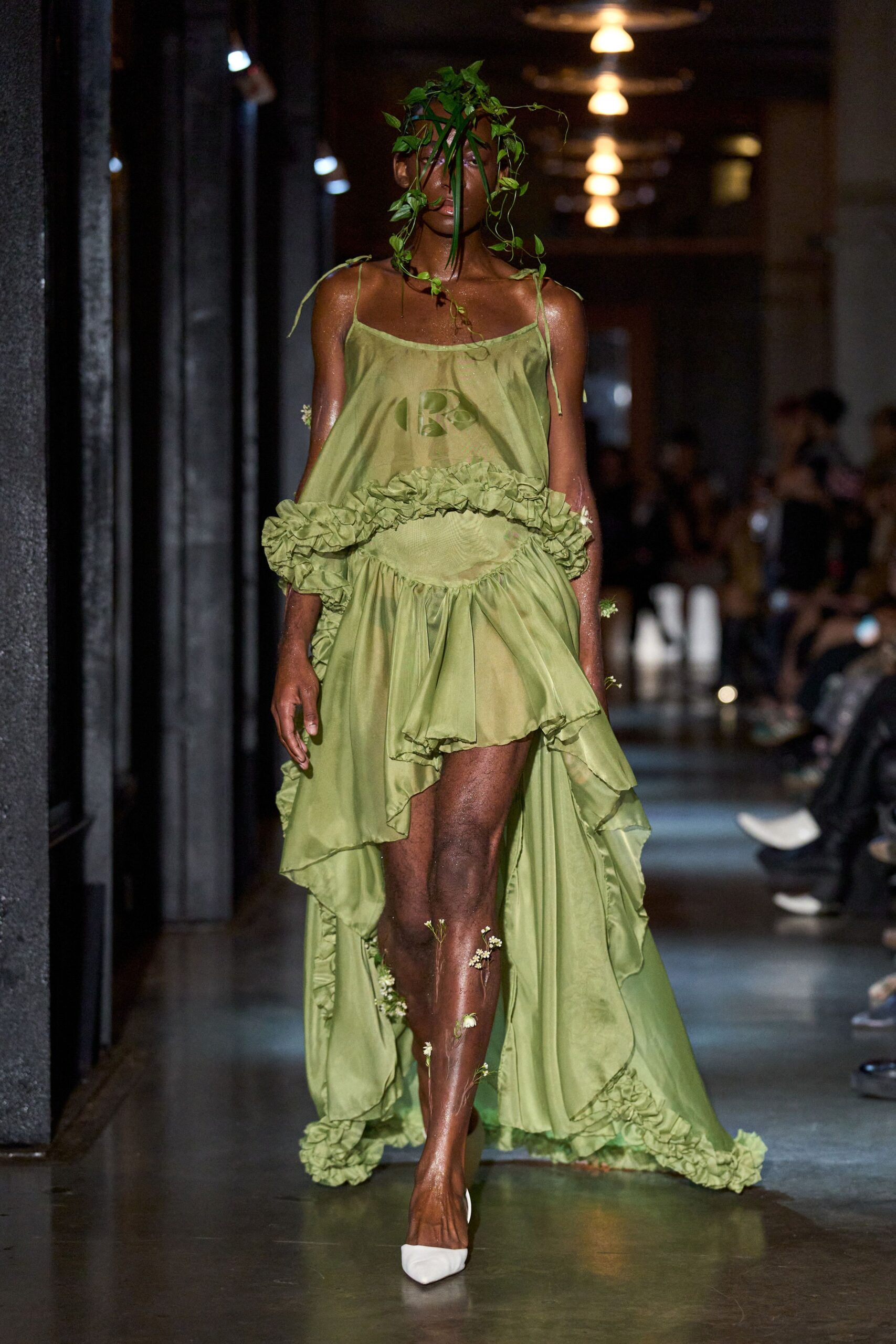 Trailing live ivy veils the face, one stem hanging past the mouth. Celadon satin slip dress with dropped ruffle and handkerchief high-low train. White pointed pumps. Walking barefoot through a conservatory after someone hosed the stone floors.