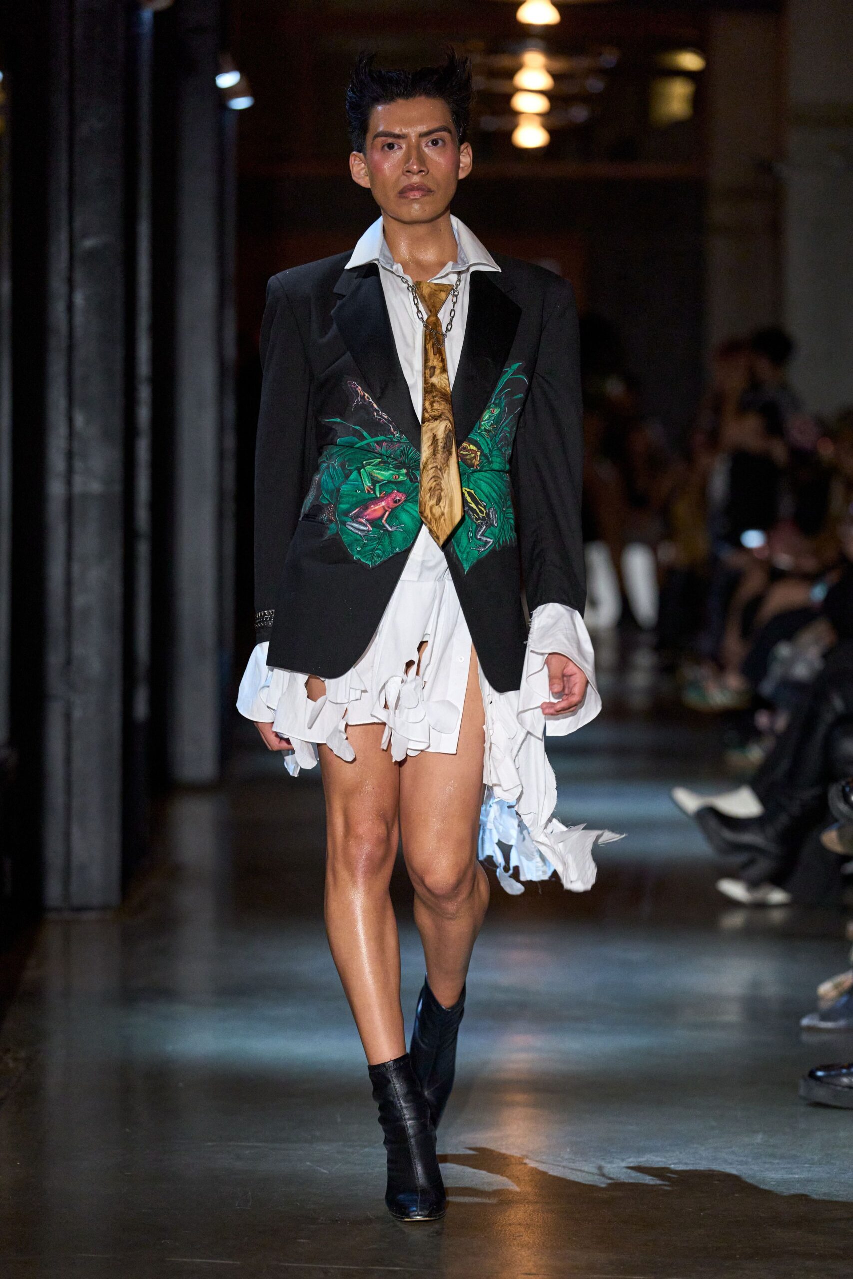 Black tuxedo blazer painted with emerald leaves and tiny frogs. White poplin shirt dress, torn into dangling strips below the blazer. Marbled ochre tie hanging loose from a chunky chain loop. Black leather ankle boots with narrow pointed toes. After midnight at a natural history museum fundraiser gone humid.