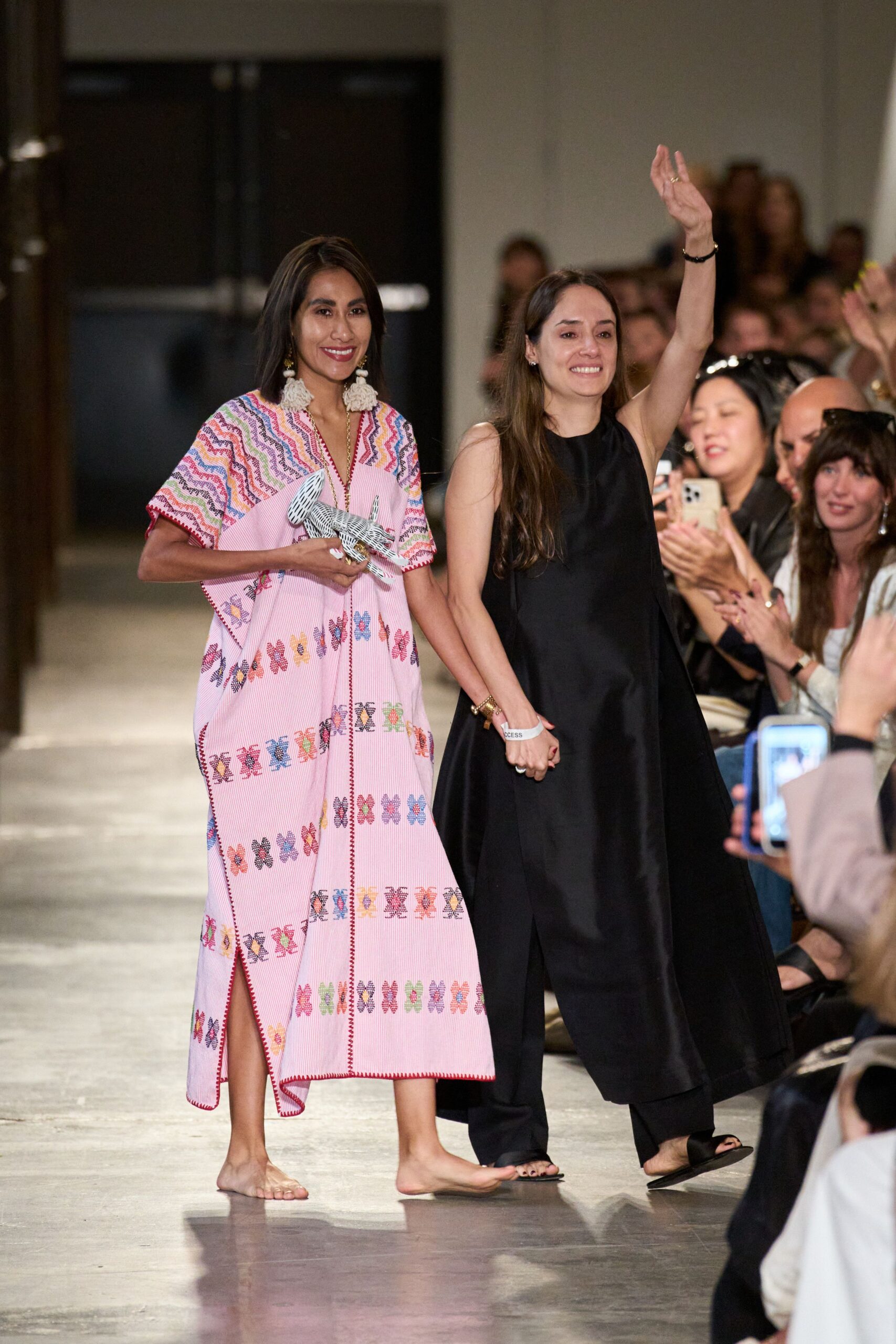 Pink pinstriped caftan with multicolor cross-stitch bands and red blanket edging. Oversized cream tassels swinging from gold drops. Barely there nude thong flats. Black-and-white striped bird clutched sideways in one hand. Walking out to applause with your shoes already kicked off.