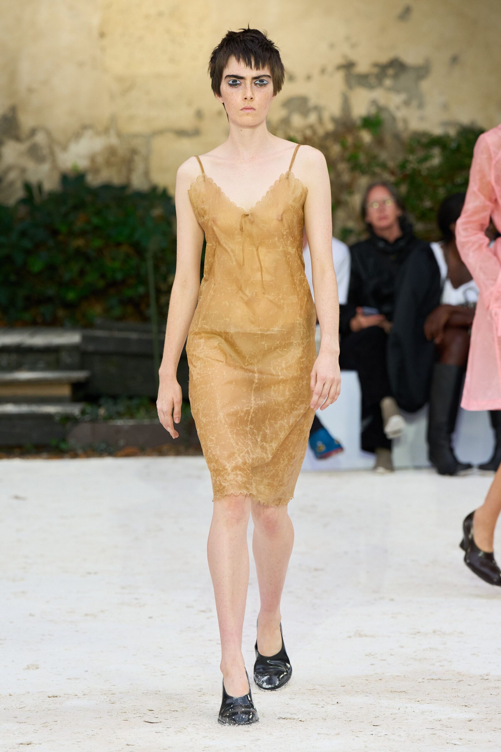 Tea-stained sheer slip dress, scalloped lace cups and a limp center bow. Black leather flats with chalky white scuffs across the toes. For walking across a villa courtyard after rain, shoes picking up the grit.