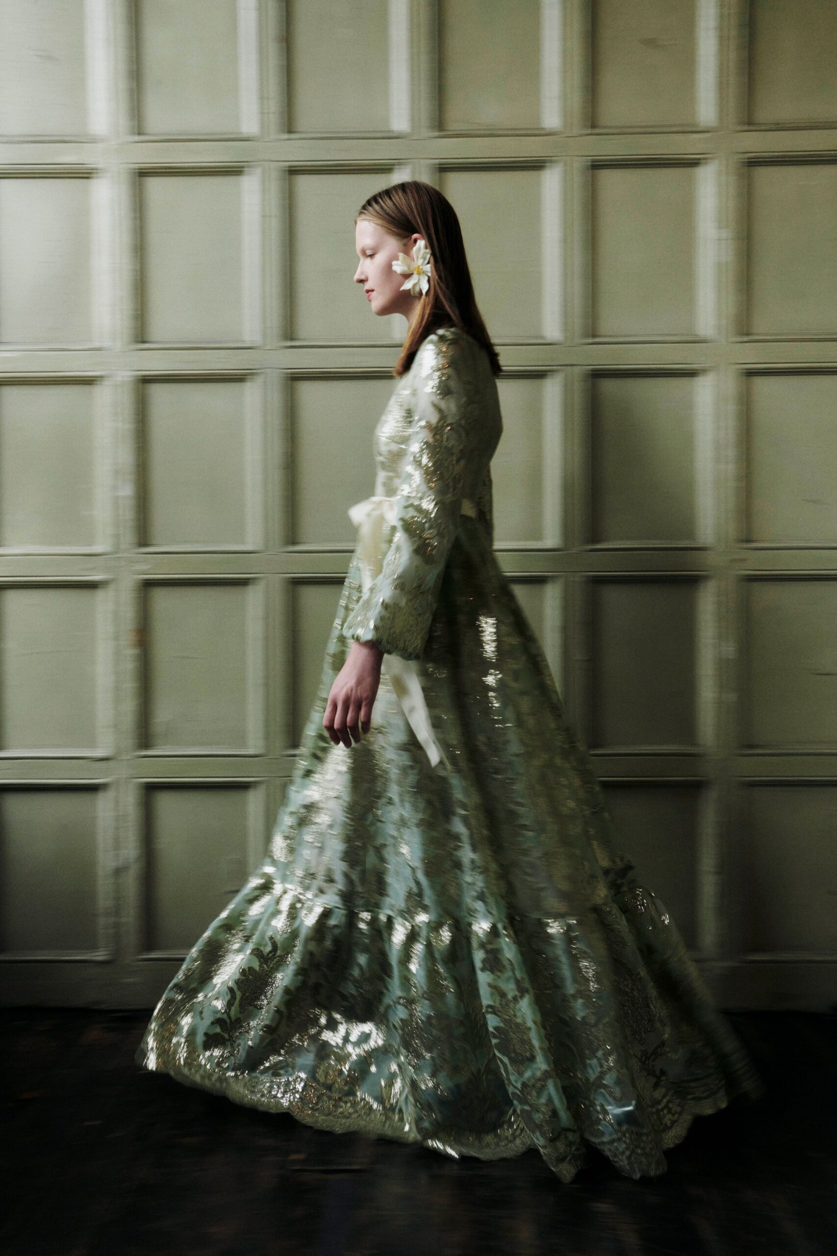 Pale celadon brocade gown, bell sleeves and a low tied ivory sash. Single white bloom tucked behind the ear. Crossing a drafty ballroom before the strings begin tuning.