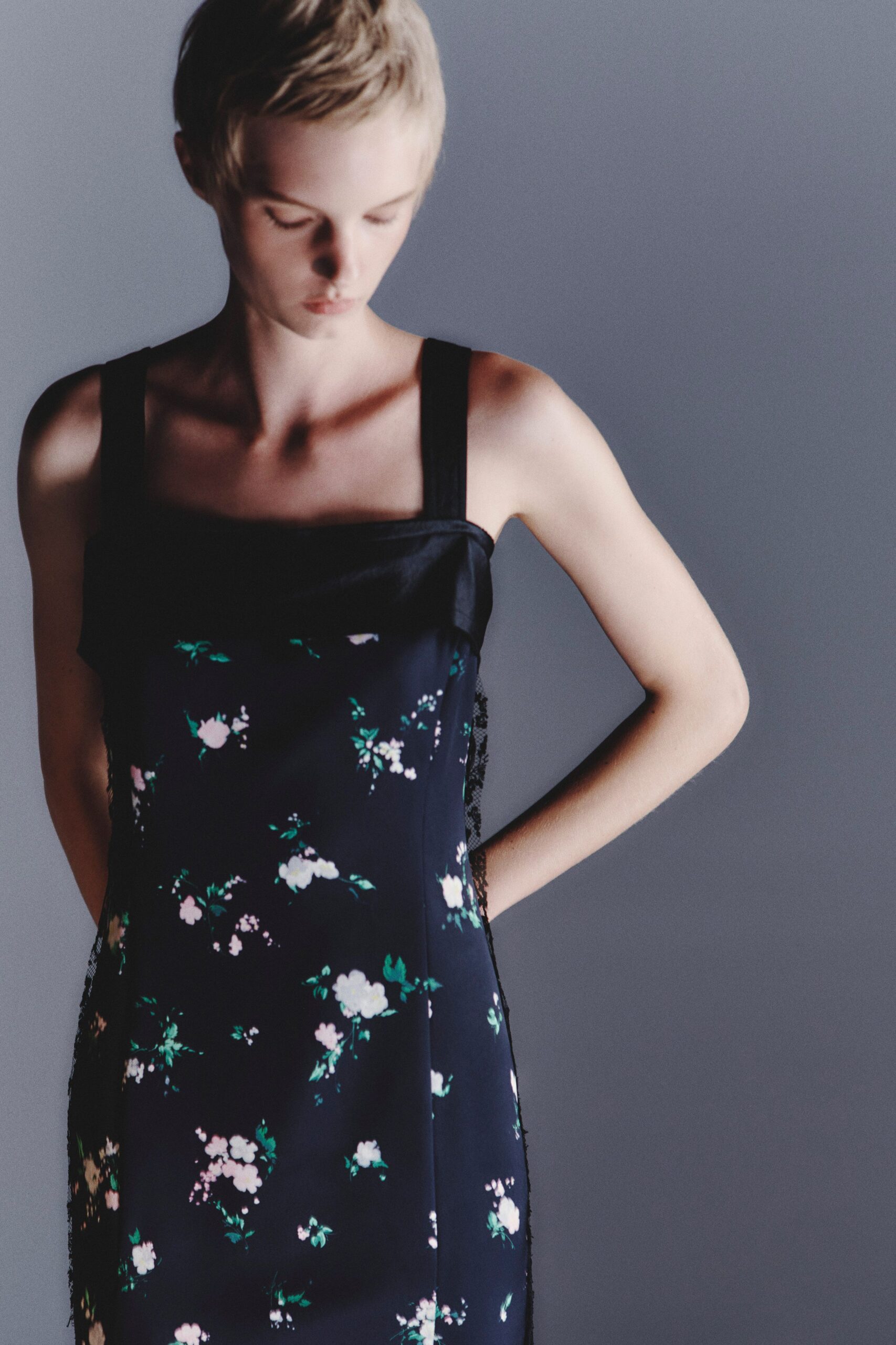 Ink-dark floral slip dress with a squared satin-trimmed neckline. Black lace edging spills past the side seams in narrow frills. Waiting by the guest-room window after everyone else has gone to bed.