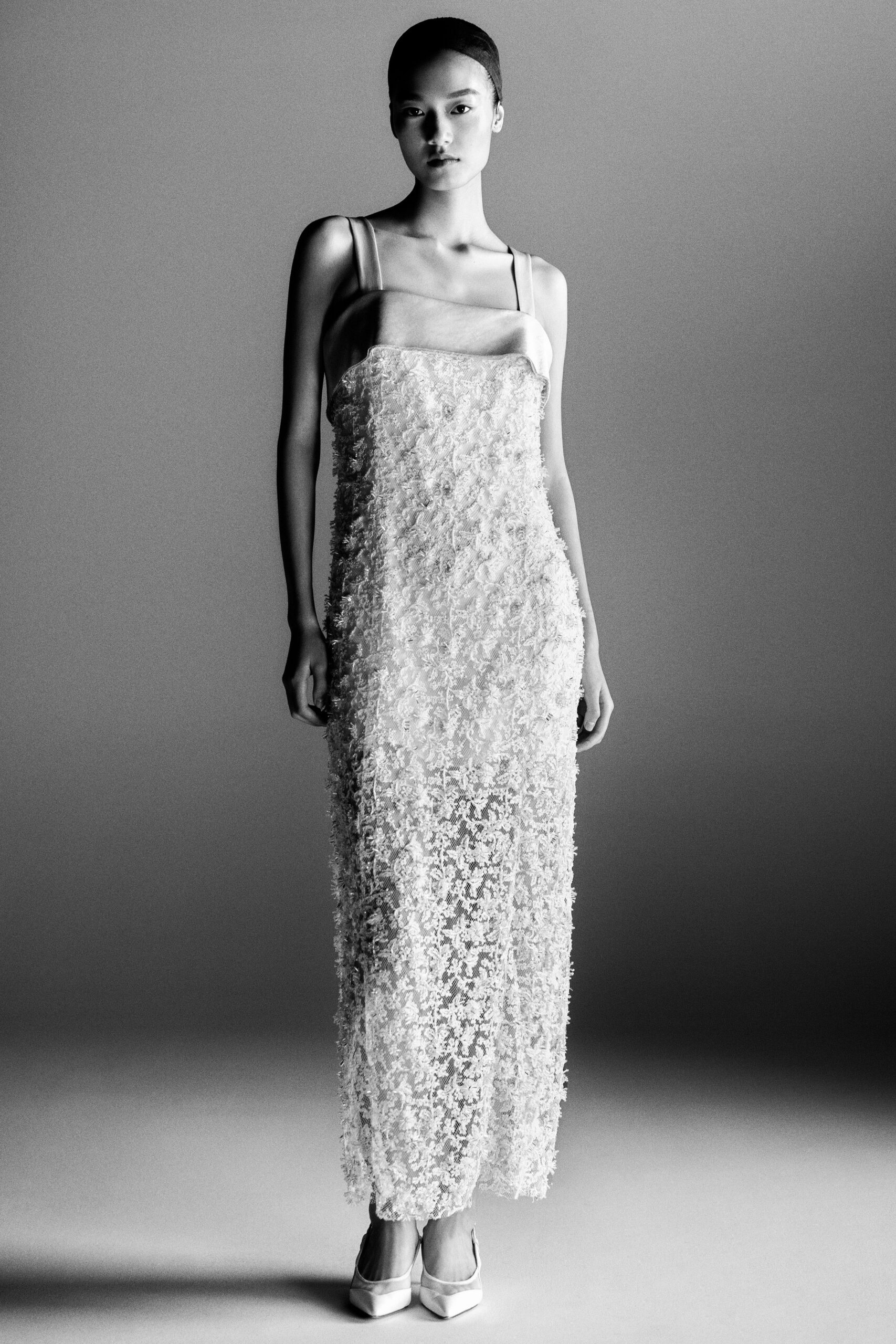 Ivory column slip with a satin bib top and dense eyelash lace. Pointed satin pumps peeking from the hem. City hall wedding, then noodles standing up before the flowers wilt.