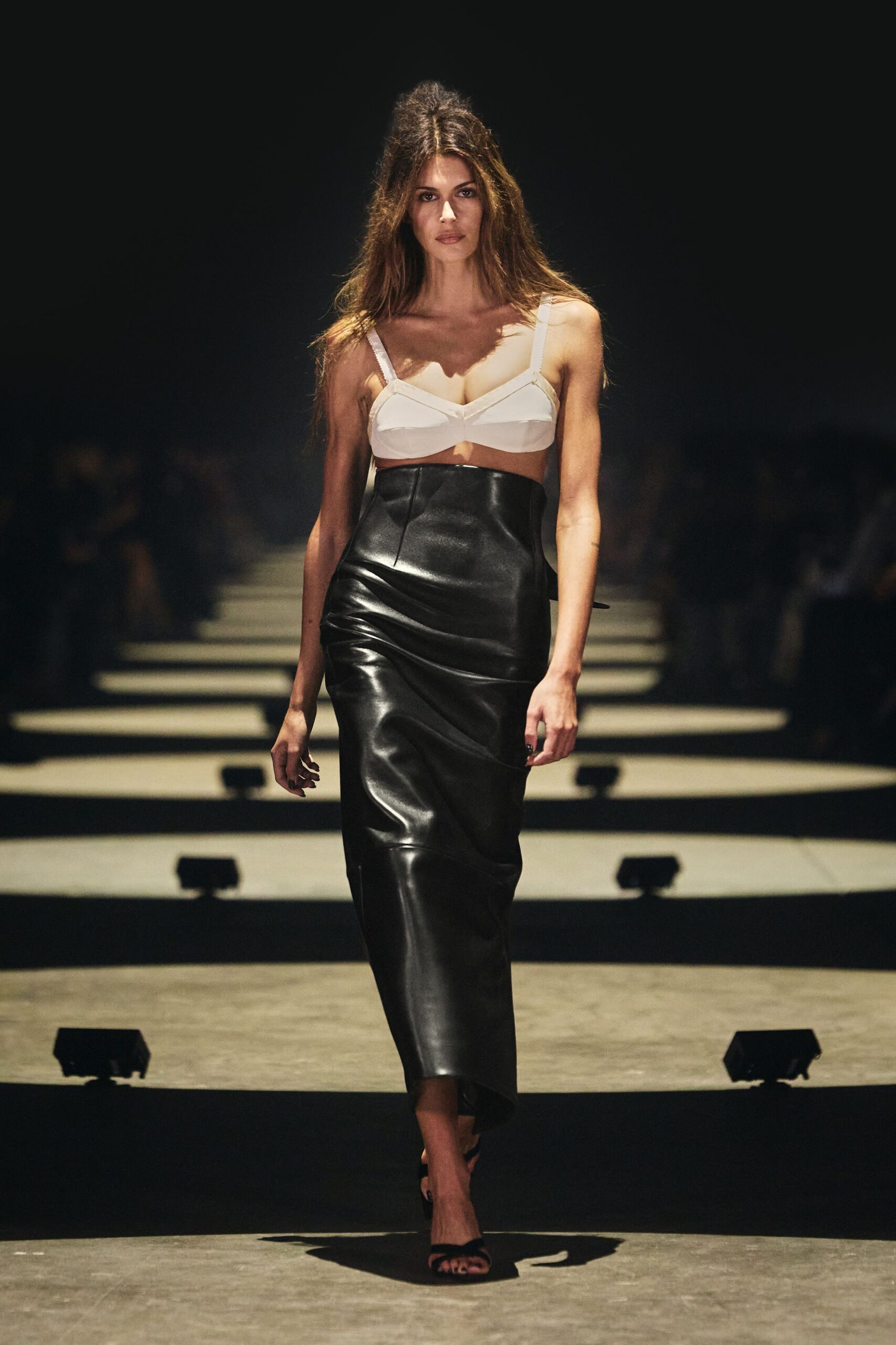 White bralette with seamed cups and narrow grosgrain shoulder straps. Black leather column skirt, cut very high with a dipped center seam. Black barely-there sandals. Whatever you wear home after missing the coat check ticket.