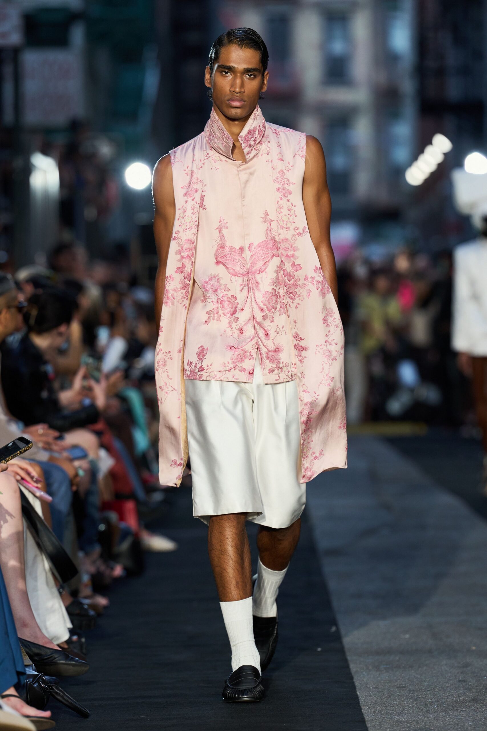 Blush satin tunic with mandarin collar and pink phoenix toile. Ivory tailored shorts cut wide through the thigh. White ribbed crew socks. Black loafers with a gathered apron toe. Crossing Chinatown at dusk with takeout still warming your hands.