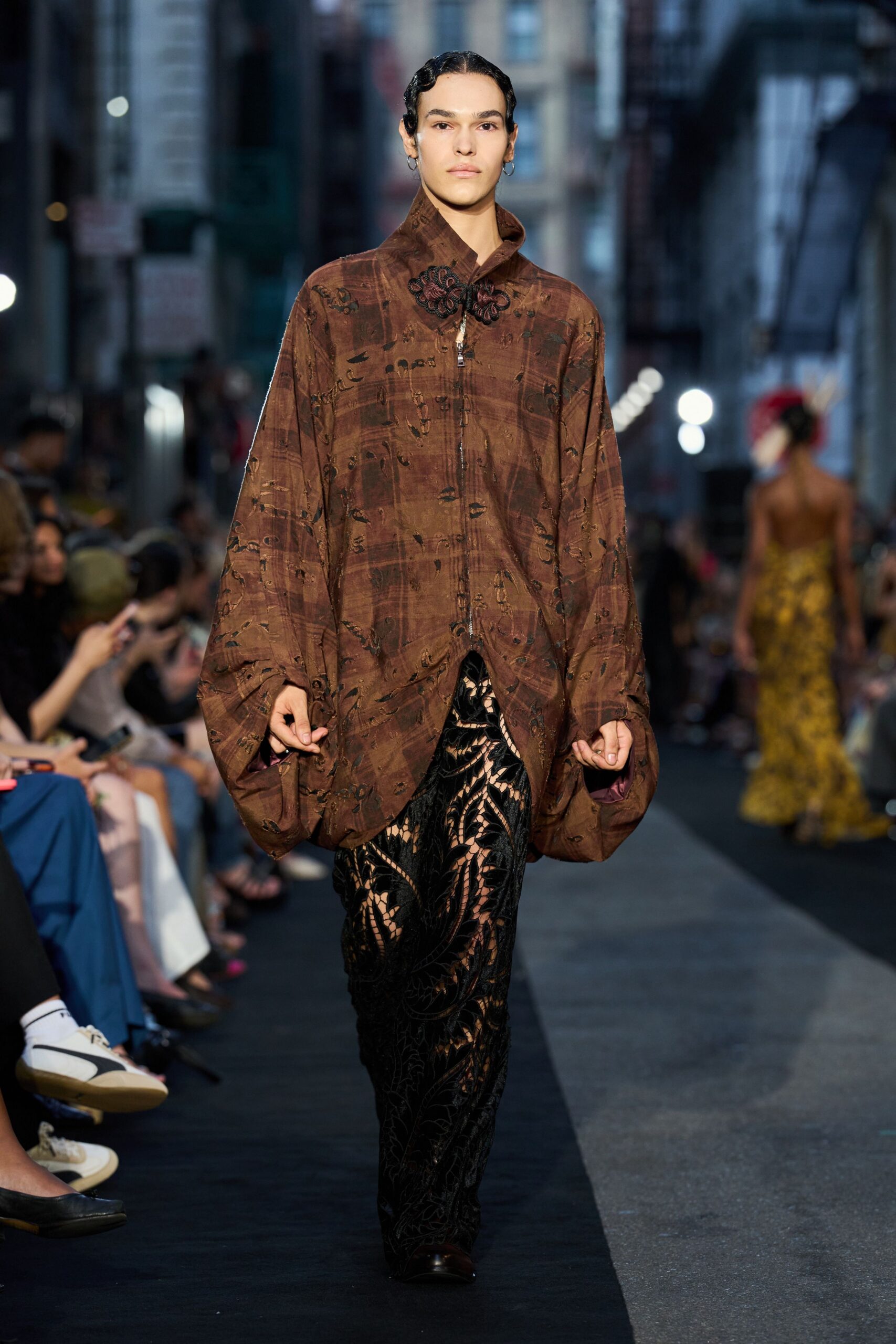 Tobacco jacquard blouson with balloon sleeves and a frog fastening at the throat. Black devore trousers, sheer swirls cut through to a nude underlayer. Small silver hoops. Walking home from Chinatown after rain, soy sauce packets in your pocket.