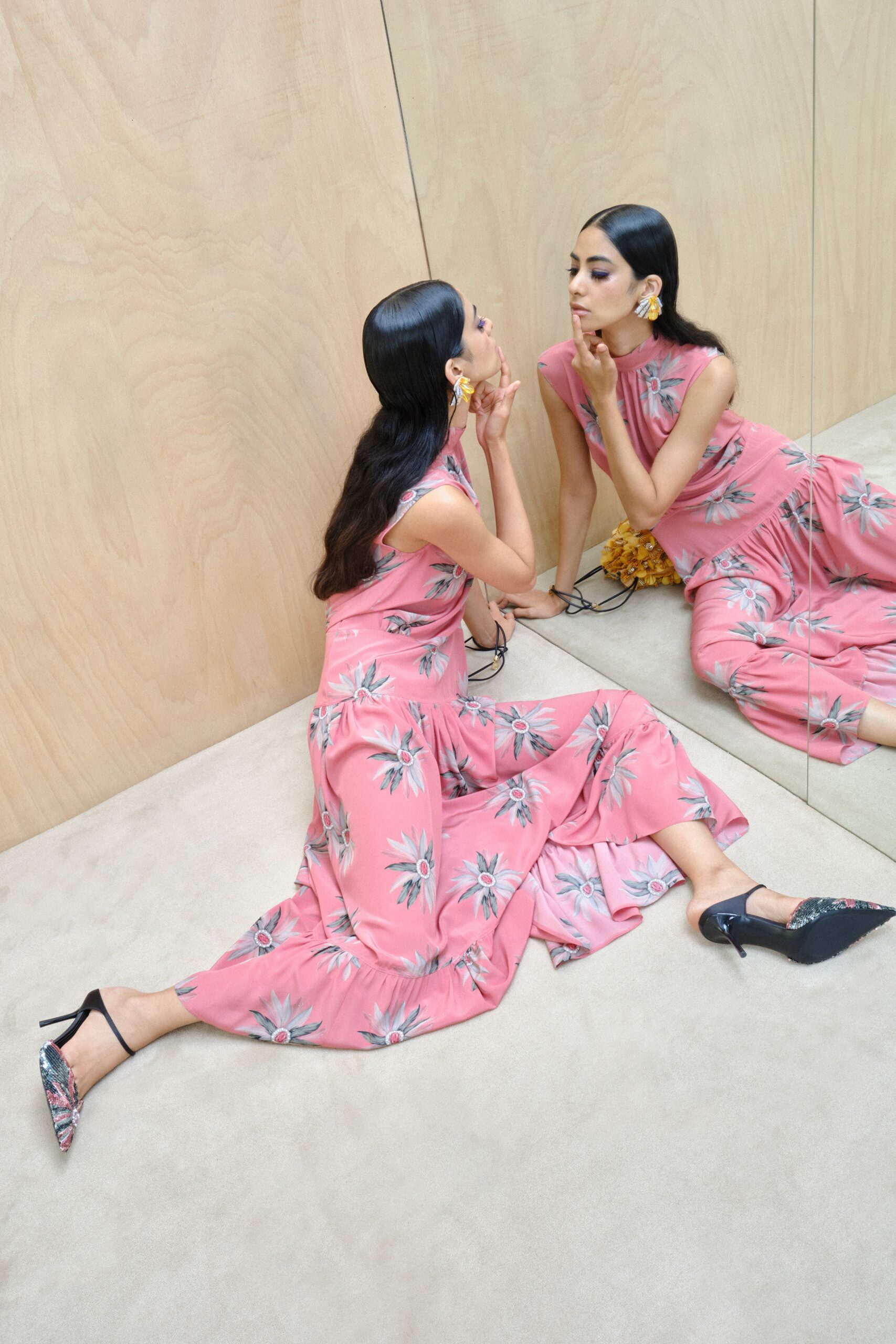 Pink satin dress scattered with grey daisies, high neck and dropped ruffle hem. Mismatched yellow petal clusters with silver crystal sprays. Black slingback stilettos with pointed floral brocade toes. Checking your lipstick in the mirrored corridor before the wedding lunch.