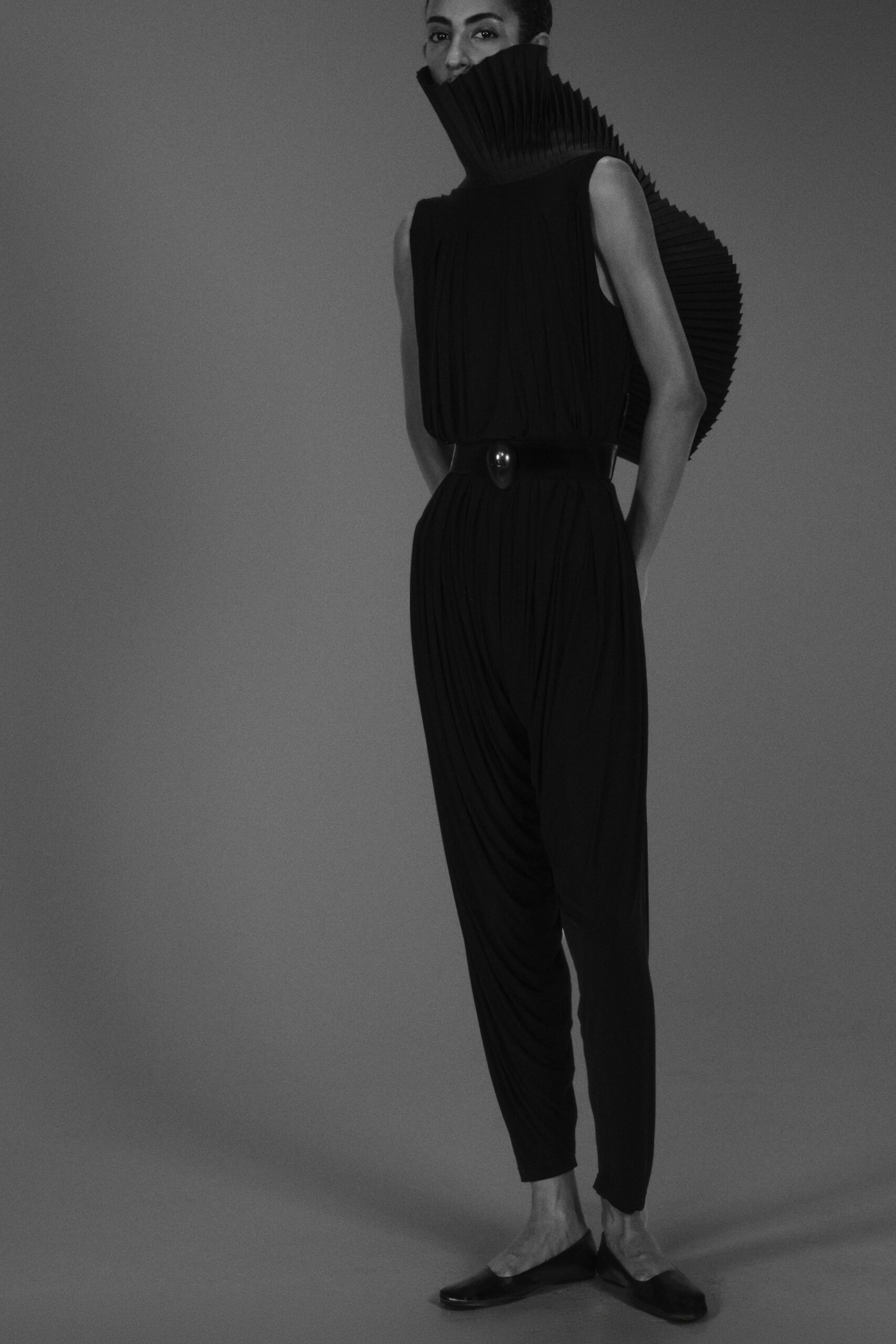 black pleated jumpsuit with sculptural collar