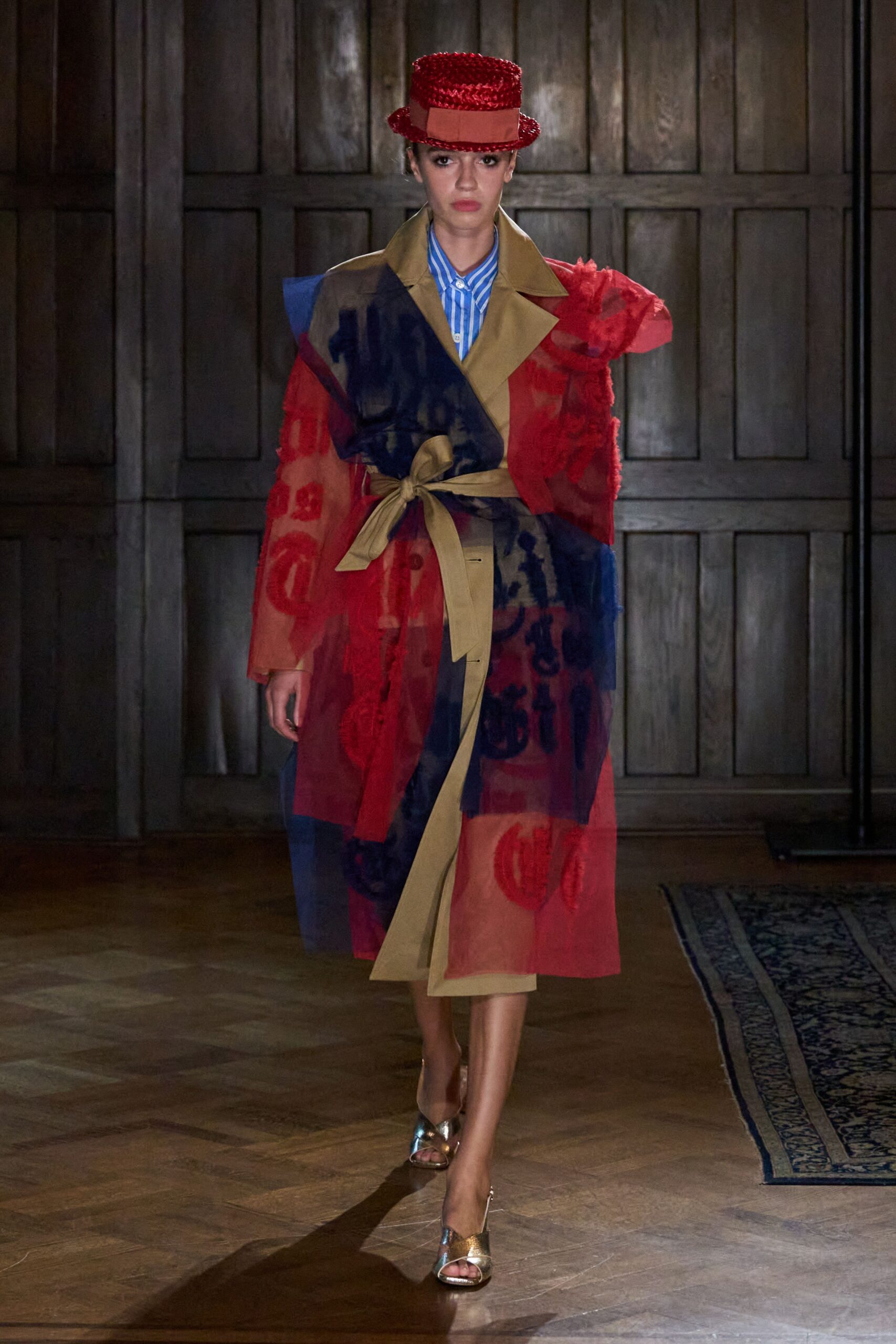 Red sequined boater hat with a grosgrain band around the crown. Blue-and-white banker striped shirt buttoned tight to the throat. Sheer red and navy organza wrap coat, khaki lapels and long sash trailing. Crinkled gold peep-toe mules. Crossing a drafty manor hallway after changing out of costume.