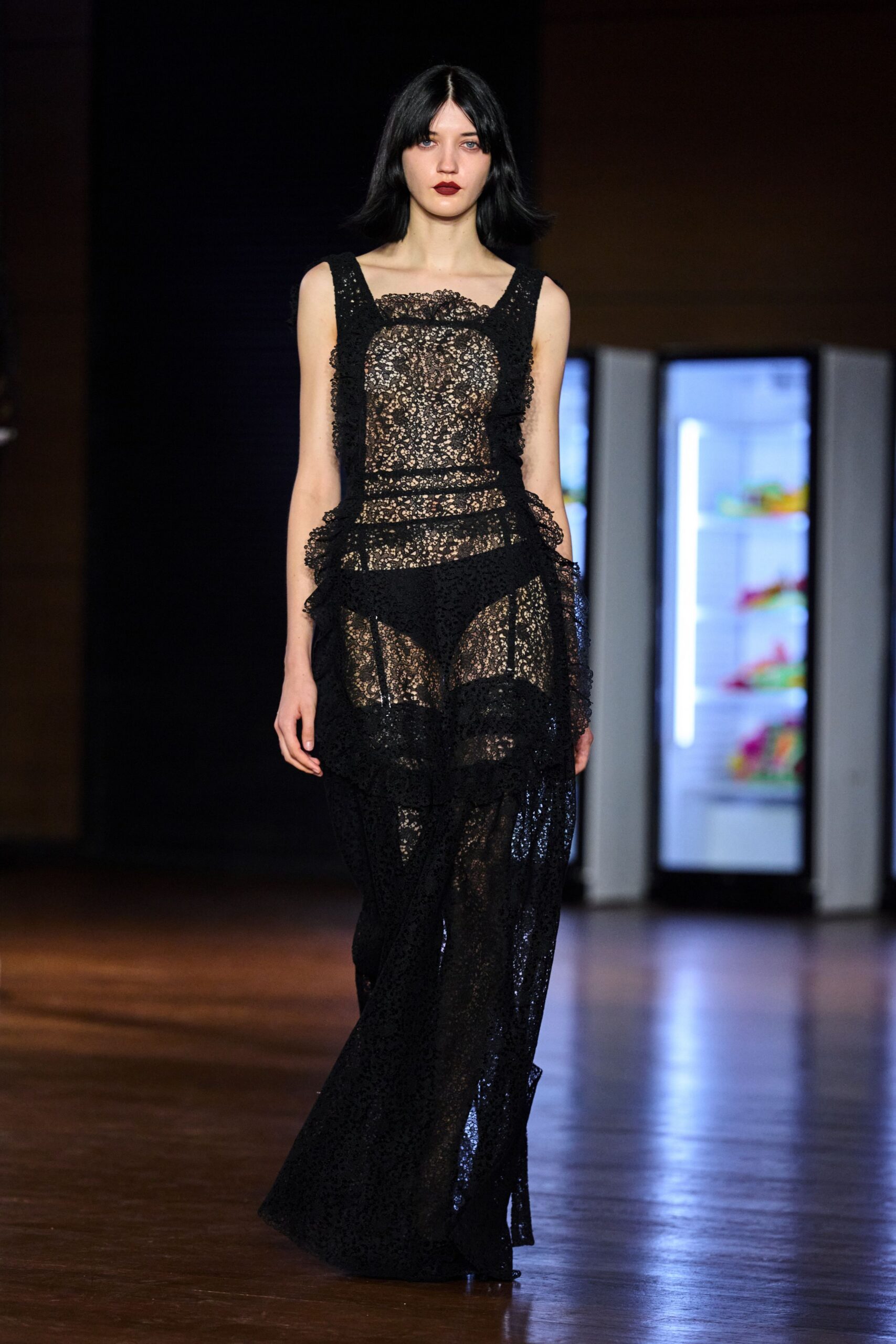 Sheer black floral lace gown with ruffled panels jutting from the hips. Opaque black briefs built in beneath the scalloped lace. Whatever you wear home when sunrise catches in the hotel atrium.