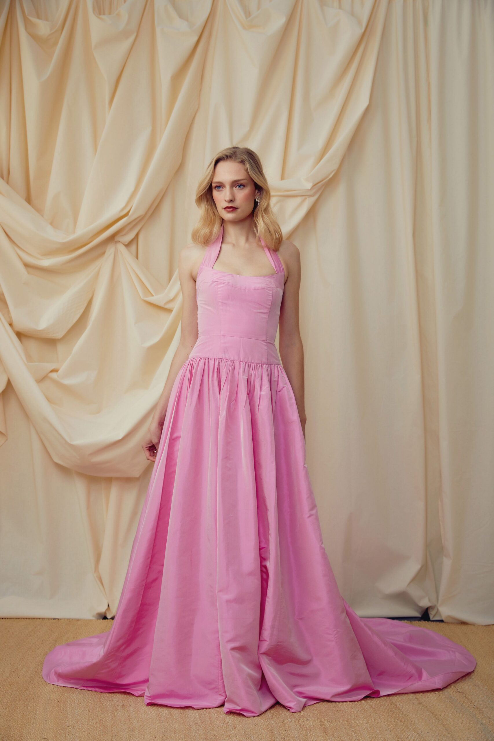 Pink taffeta halter gown with a square neckline and pooled train. Small crystal cluster drops at the lobes. For cutting the cake in a rented hall with curling ribbon underfoot.
