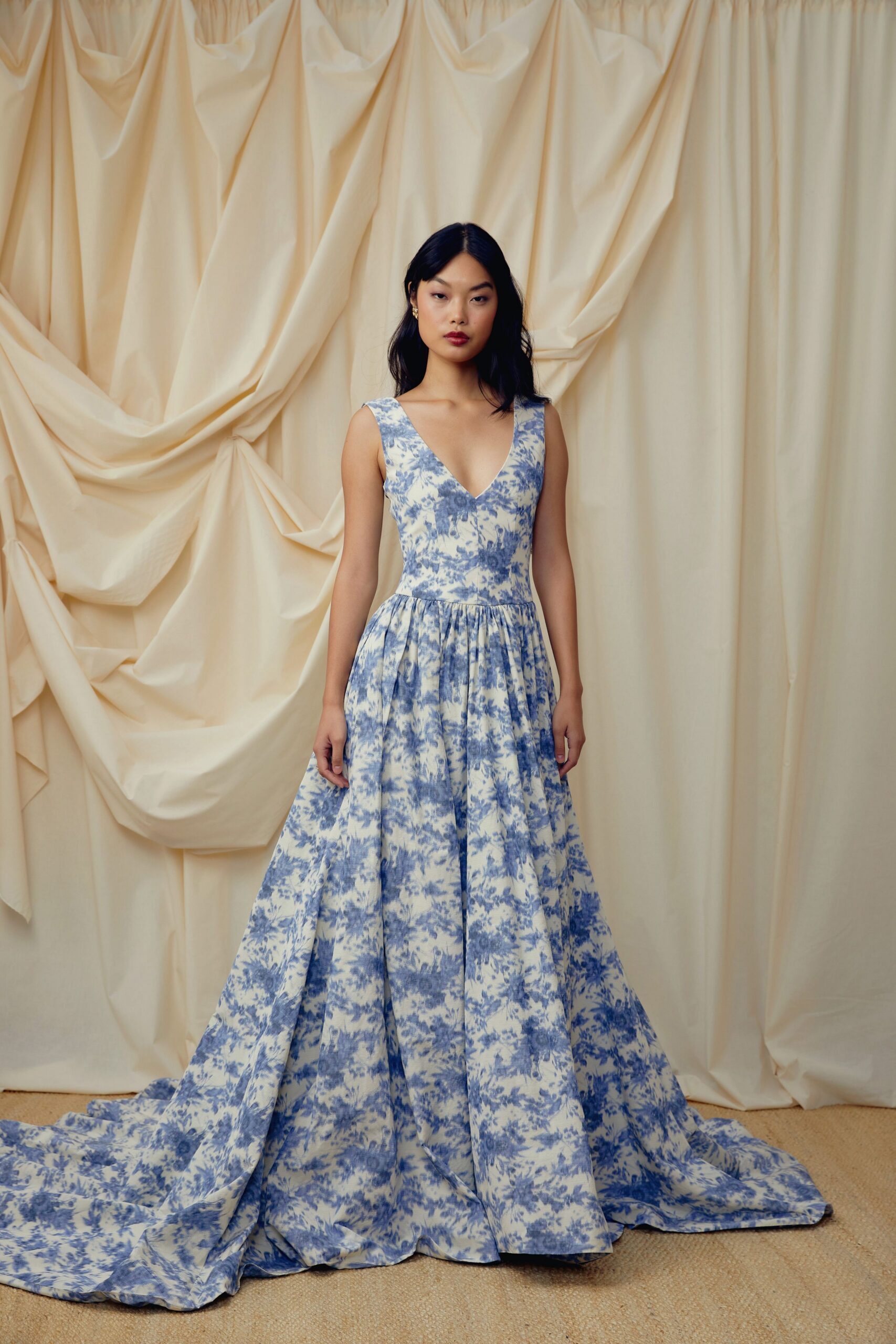 Blue toile floral gown with a plunging V bodice and box-pleated skirt. Tiny gold floral studs. For the first dance in a rented villa with the shutters open.