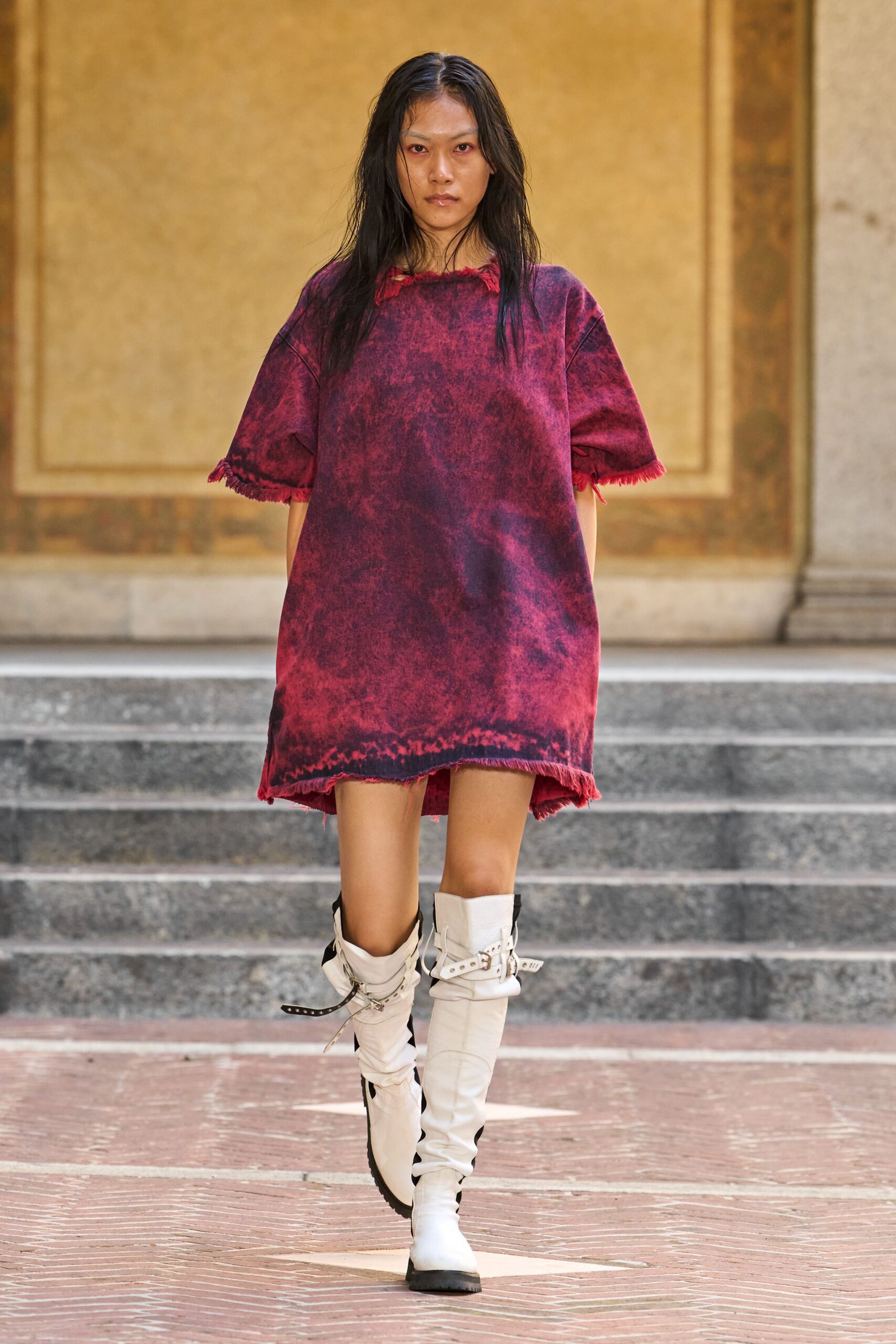 Acid-washed crimson shift dress, raw fringing at neck, cuffs and hem. Slouched bone leather boots with strapped buckles and one loose tail. Crossing a cold cloister courtyard before the bells finish.