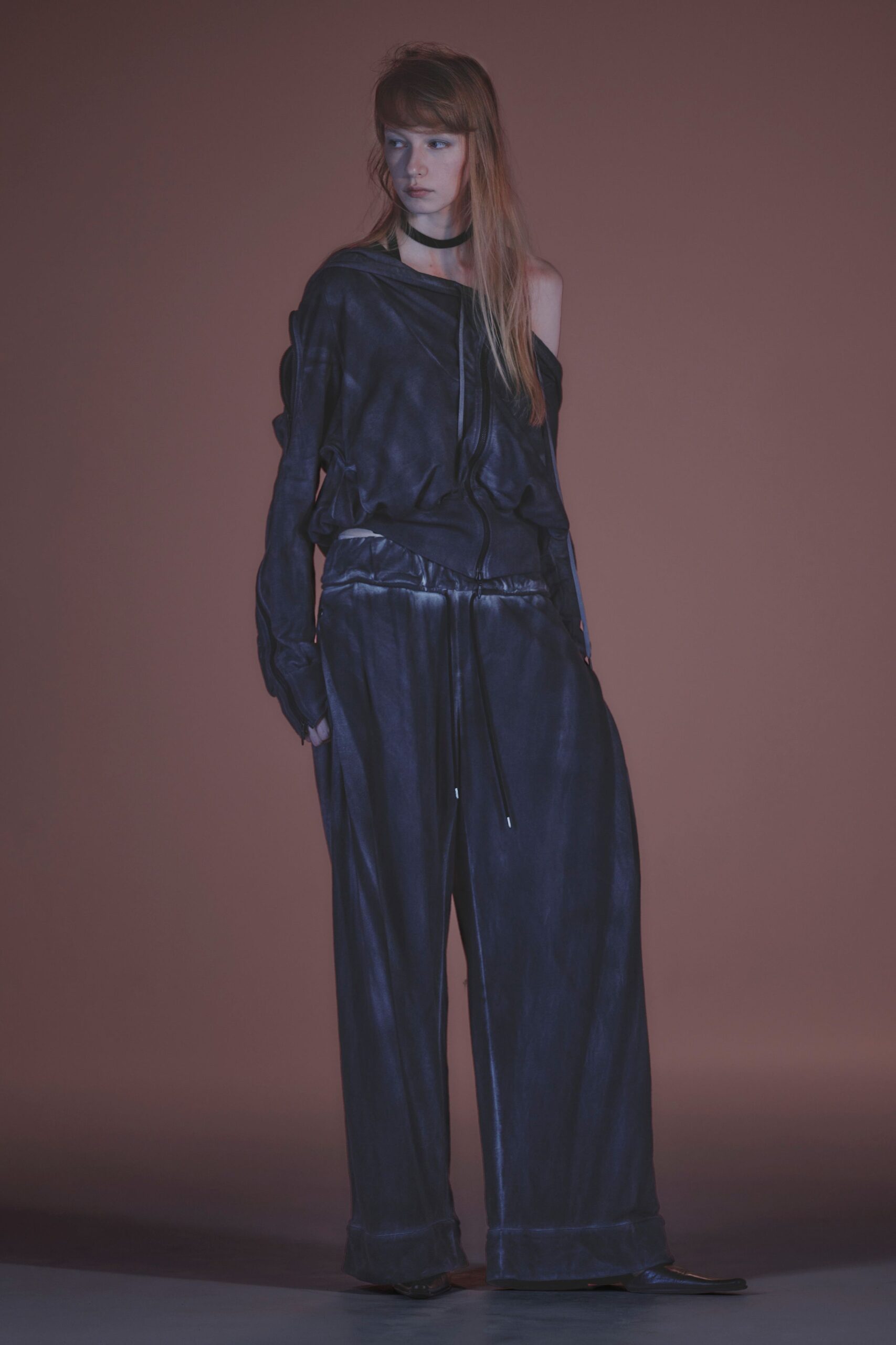 Inky satin top slouched off one shoulder, zip running crookedly down the front. Narrow black velvet band at the throat. Pooling satin wide-legs with a glossy pieced waistband and drawcord tips. Squared black flats peeking from the hem. Whatever you wear home after missing the last train in damp heat.