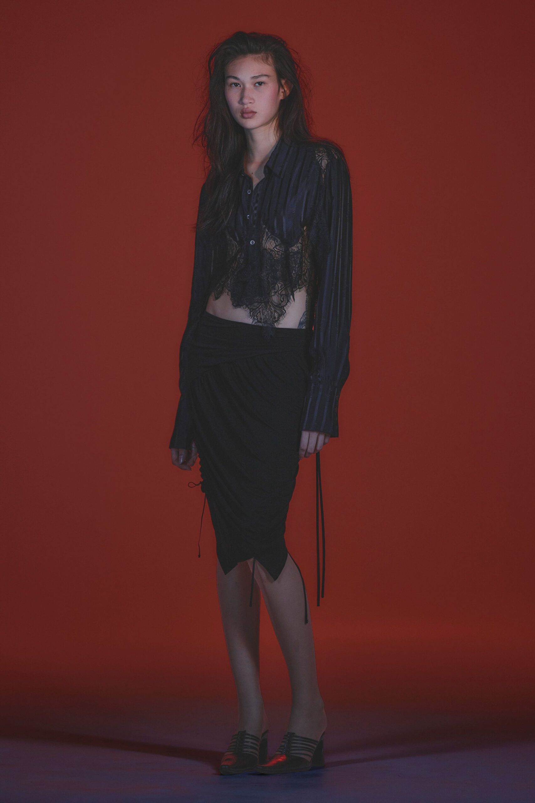 Inky striped blouse cut away into scalloped black lace at the midriff. Black draped skirt with a folded waistband and dangling drawcord ends. Black cage-front mules on a low wedge. Walking out to the hotel corridor ice machine after midnight.