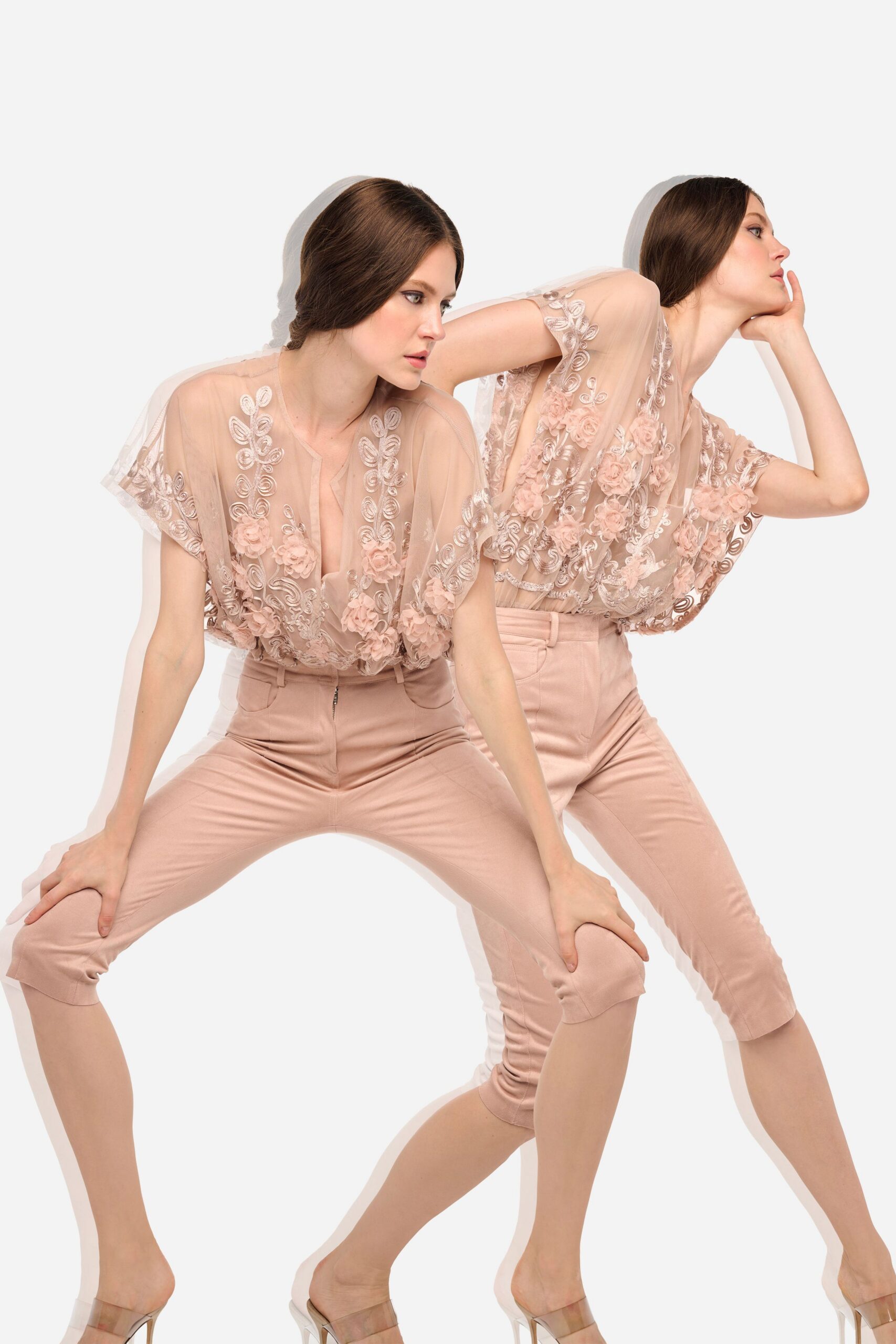 Blush illusion tulle blouse with soutache swirls and clustered rosettes. High-waisted blush sateen capris, front zip catching at the waistband. Clear PVC mules with slim stiletto heels. Walking into a hotel atrium wedding before the string quartet starts.